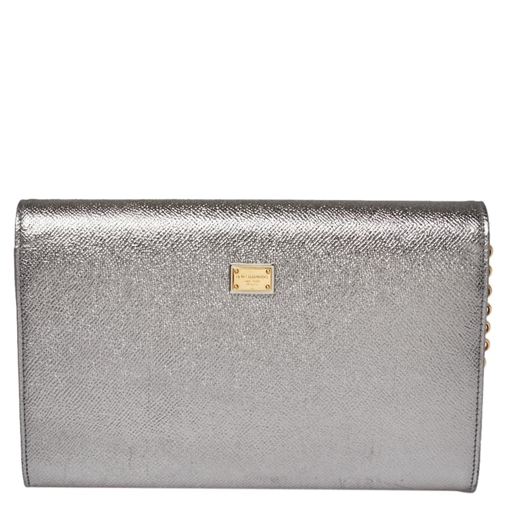 This Dolce & Gabbana clutch is crafted from metallic silver leather. It has a simple silhouette and features 'MILLENIALS' on the front flap. With a leather-lined interior, the bag has a zip pocket and enough space to house your necessities. It is