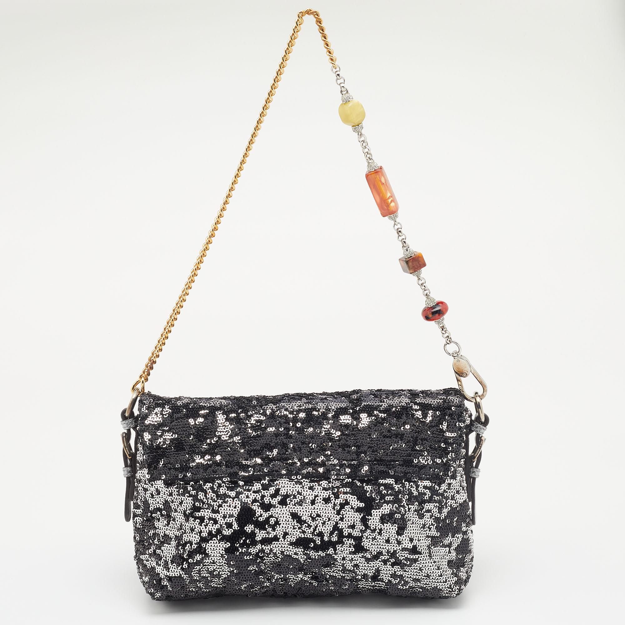This shimmering Miss Charles bag from the House of Dolce & Gabbana is a lovely evening handbag. It is made from metallic silver sequins and is highlighted with gold-tone hardware. It is completed with a decorative shoulder strap and a suede-lined