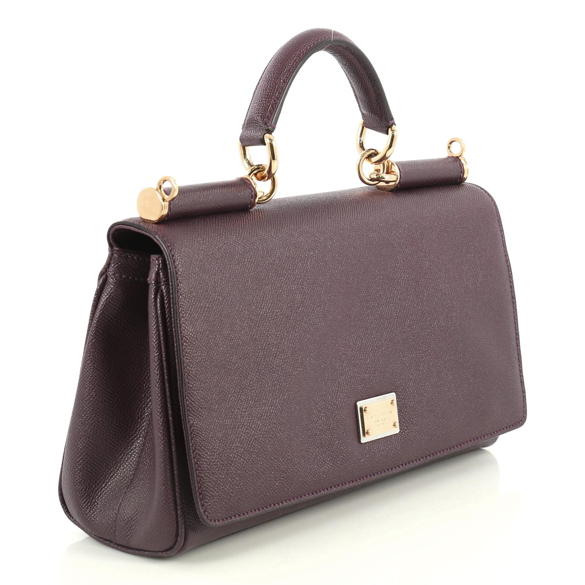 This Dolce & Gabbana Miss Sicily Bag Leather Medium, crafted in purple leather, features a leather top handle and gold-tone hardware. Its framed top flap with magnetic snap closure opens to a brown printed fabric interior with zip and slip pockets.