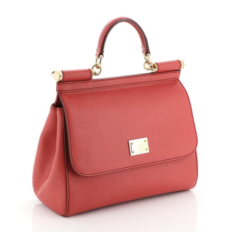 This Dolce & Gabbana Miss Sicily Bag Leather Medium, crafted in red leather, features a leather top handle, protective base studs, and gold-tone hardware. Its framed top flap with magnetic snap closure opens to a brown printed fabric interior with