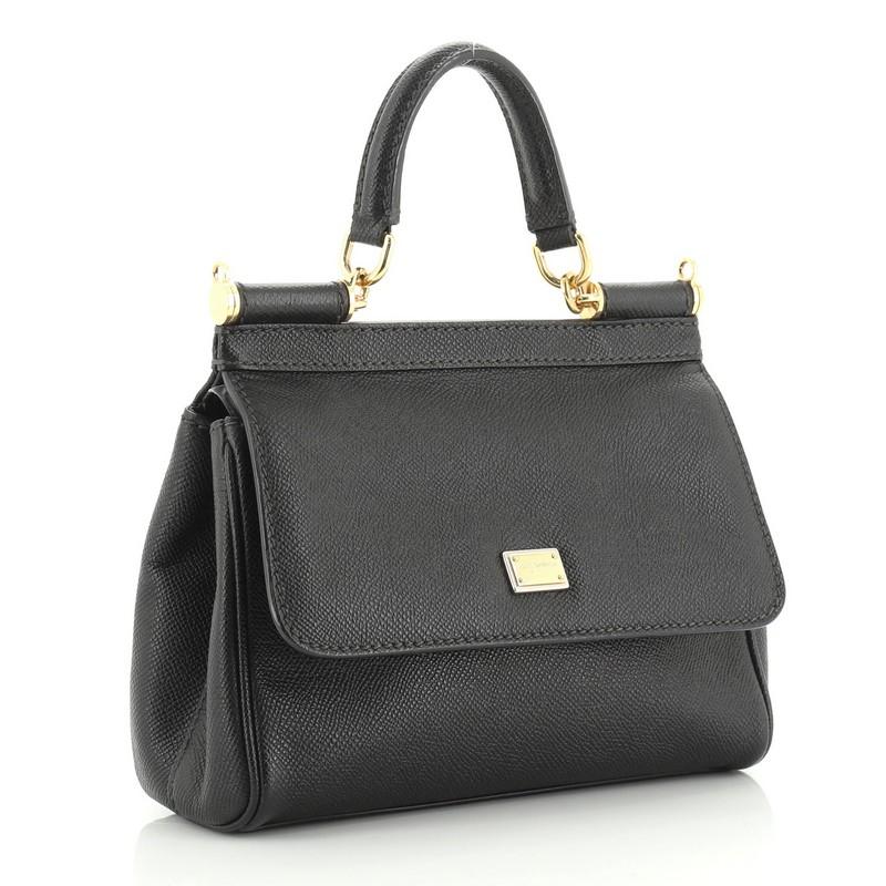 This Dolce & Gabbana Miss Sicily Bag Leather Small, crafted in black leather, features a leather top handle, protective base studs, and gold-tone hardware. Its framed top flap with magnetic snap closure opens to a brown fabric interior with zip and