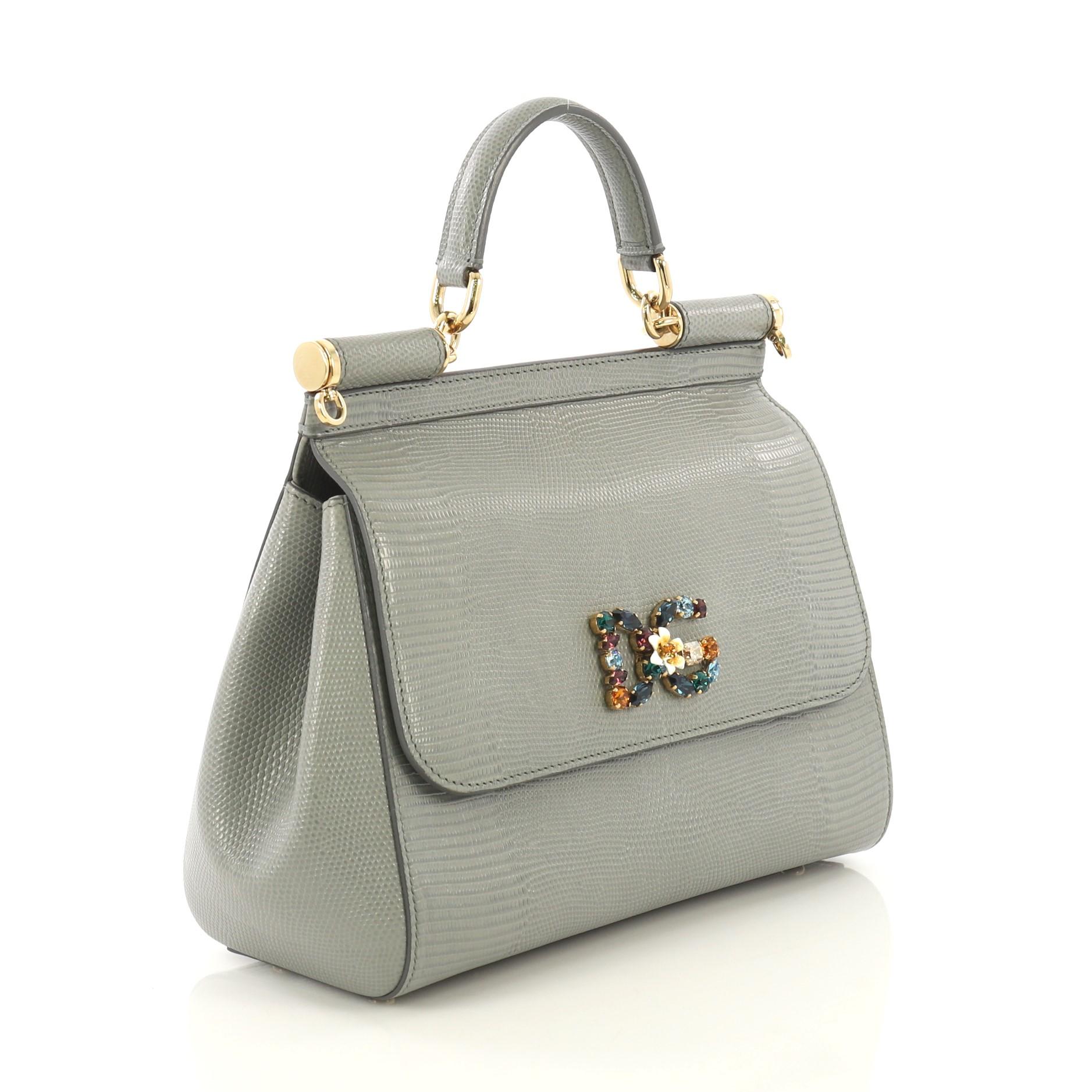 This Dolce & Gabbana Miss Sicily Bag Lizard Embossed Leather Medium, crafted in gray lizard embossed leather, features a leather top handle, framed top flap, and gold-tone hardware. Its magnetic snap closure opens to a brown leopard print fabric