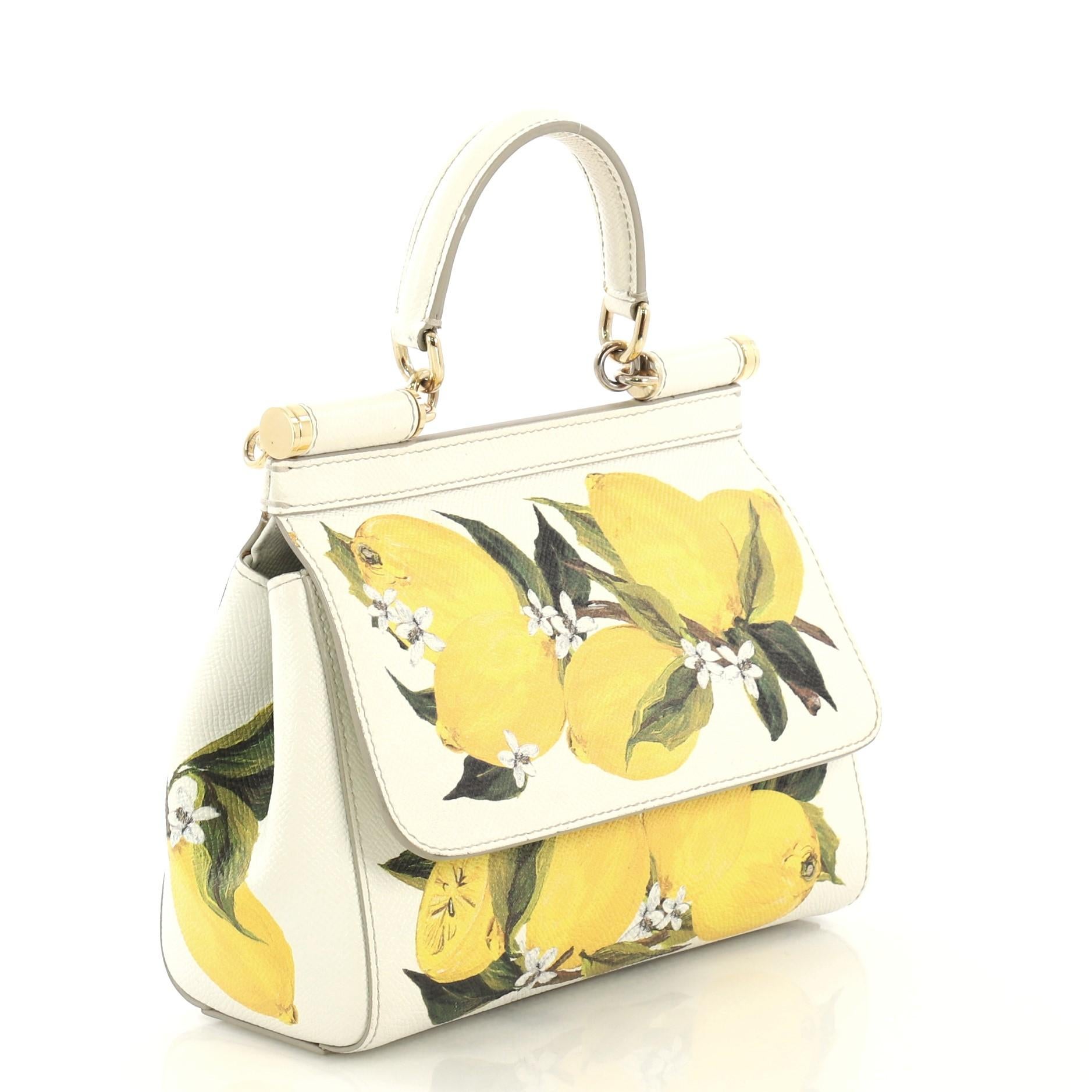 This Dolce & Gabbana Miss Sicily Bag Printed Leather Small, crafted in white printed leather, features a single looped leather handle, frontal flap and gold-tone hardware. Its magnetic snap closure opens to a black fabric interior with slip pockets.