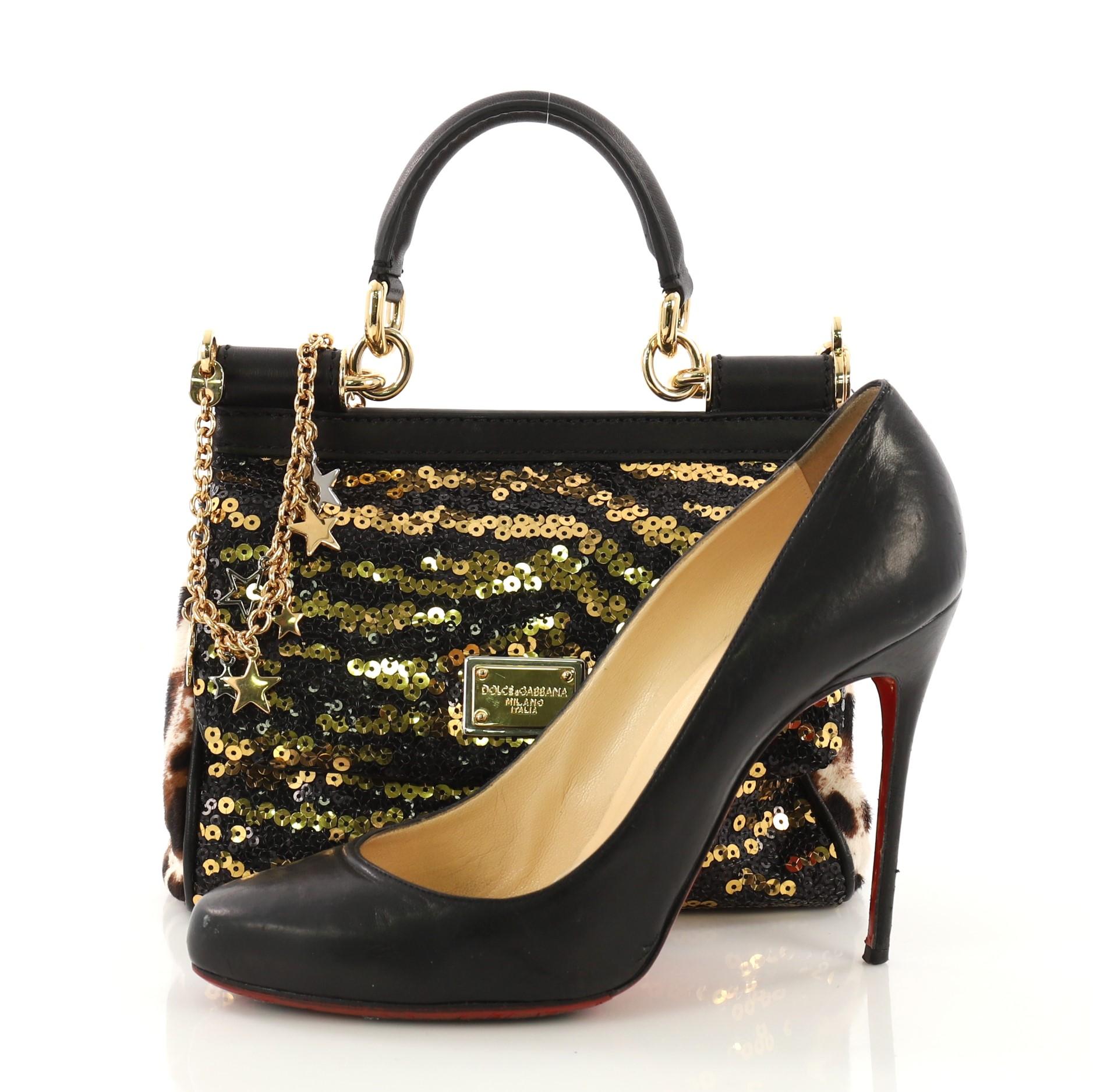 This Dolce & Gabbana Miss Sicily Handbag Sequins Small, crafted from black and gold sequins, features a leather top handle, designer plaque, framed top and gold-tone hardware. Its magnetic snap closure opens to a navy fabric interior with slip