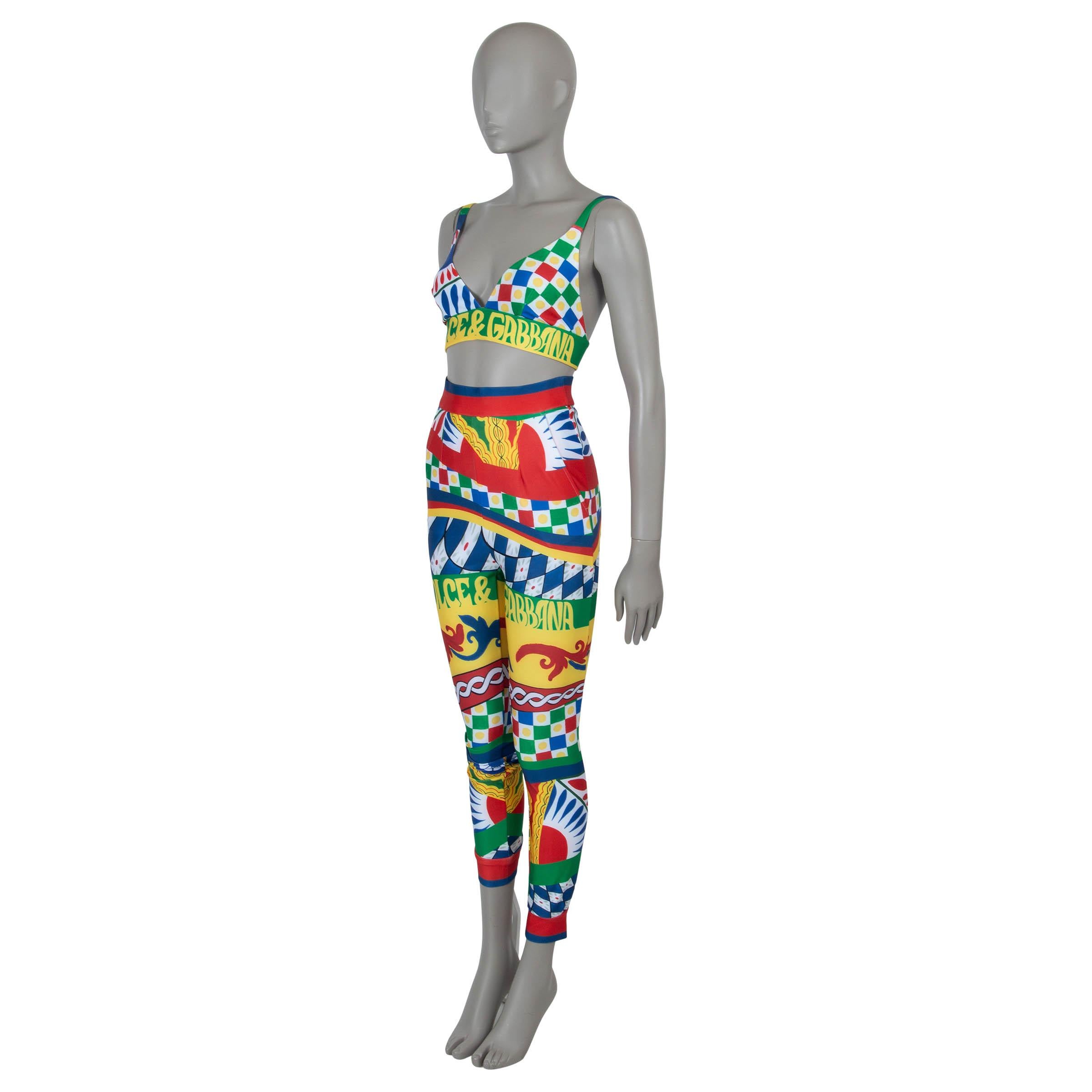 This 100% authentic Dolce & Gabbana outfit in multicolor technical jersey polyamide (50%), polyester (30%), and elastane (20%) showcases the vibrant Carretto print. The bralette top features a cropped length, logo band, adjustable spaghetti straps,