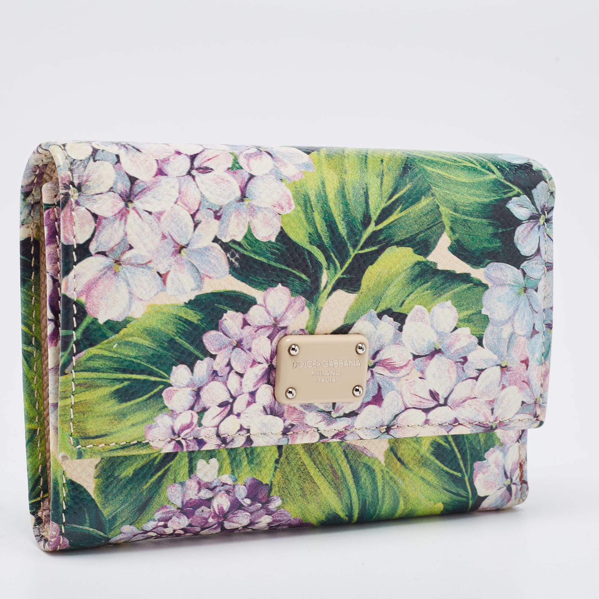 This beautiful Dolce & Gabbana trifold wallet is crafted from leather and features a lovely floral print. It opens to a leather and fabric lined interior that has a slot for you to arrange your currency and bills and a coin pocket. This sleek and