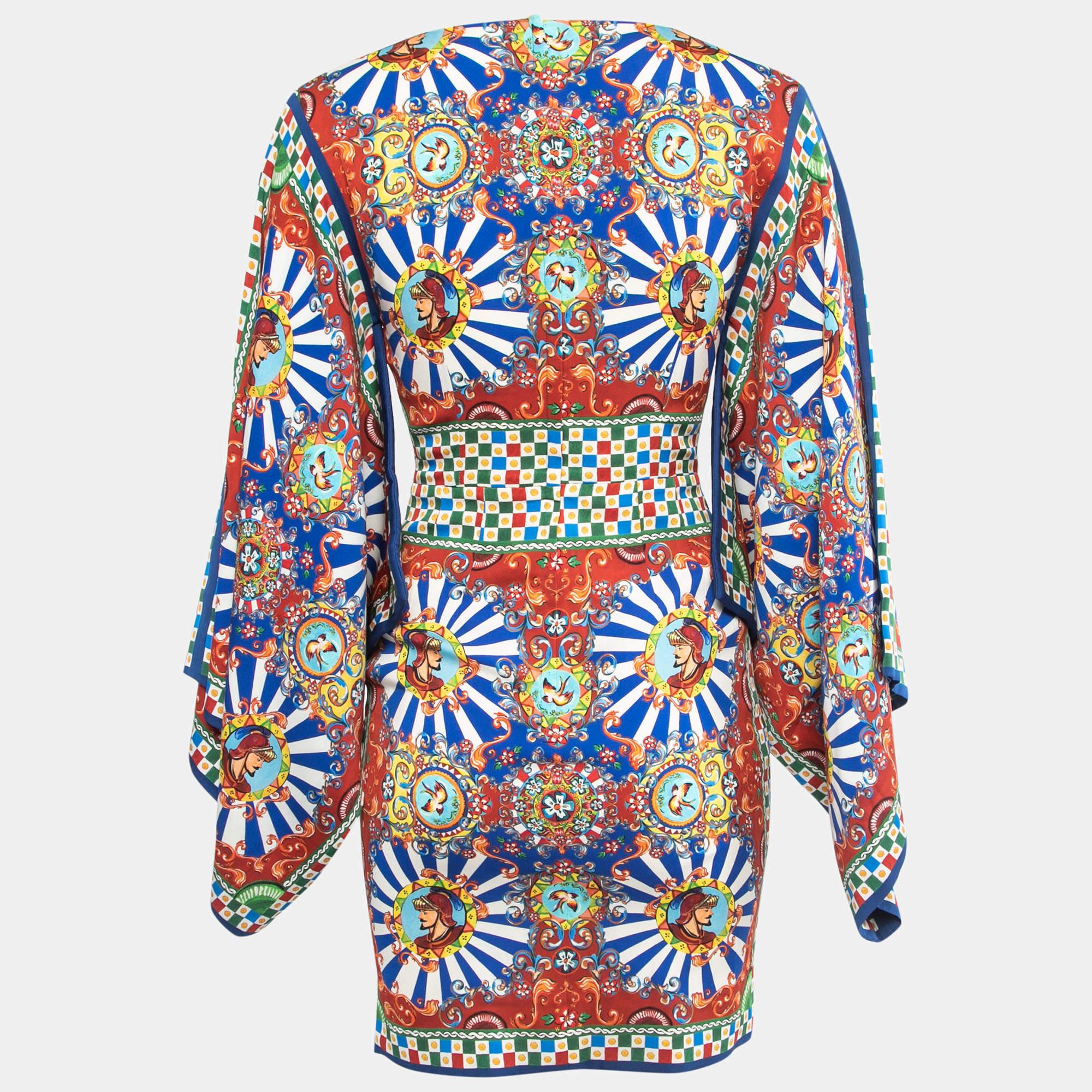 The Dolce & Gabbana dress is a vibrant and eye-catching piece. Made from luxurious silk, it features a colorful print that adds a playful and artistic touch. The dress has wide kimono sleeves, giving it a relaxed and elegant look, while the short