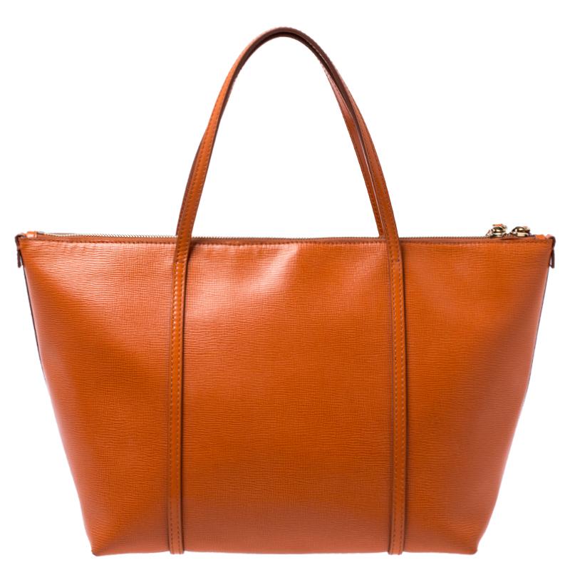 This stunning Escape shopper tote is from the house of Dolce & Gabbana. Crafted from leather, and lined with suede on the insides, the bag features a bright orange exterior with dual top handles and a gold-tone padlock flaunted on the front. Swing