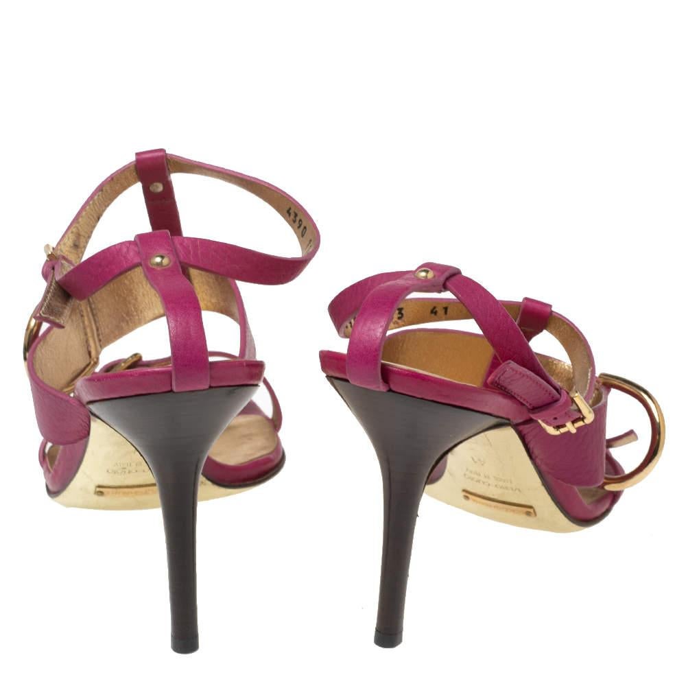 Add a pop of pink to your ensemble with these gorgeous sandals from the House of Dolce & Gabbana. Crafted from pink leather, they are embellished with gold-toned buckled details on the upper. To elevate their beauty further, they come with a T-strap