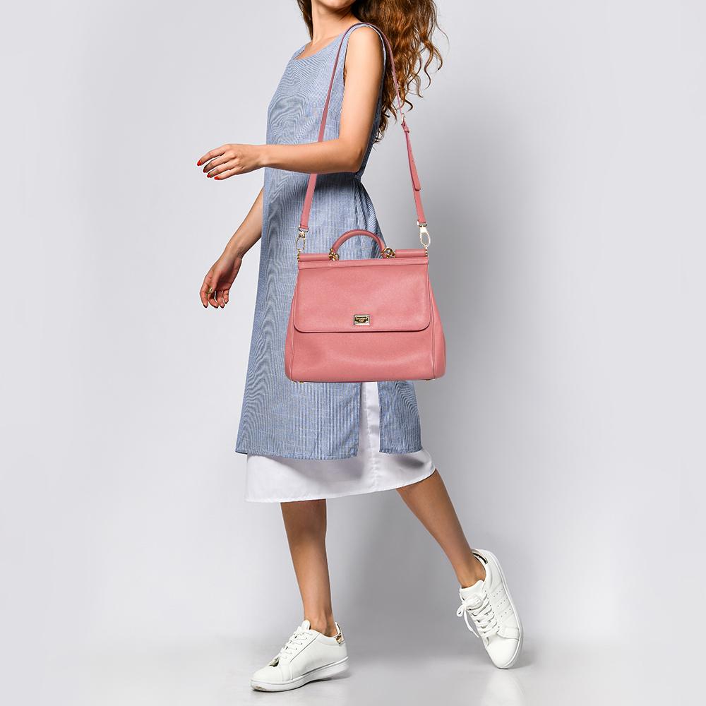 The iconic Miss Sicily bag by Dolce & Gabbana is named after Domenico Dolce's native land and exhibits the aesthetic of Italian glamour. The neat silhouette is made from leather in a pink shade and features a front flap accented with the signature