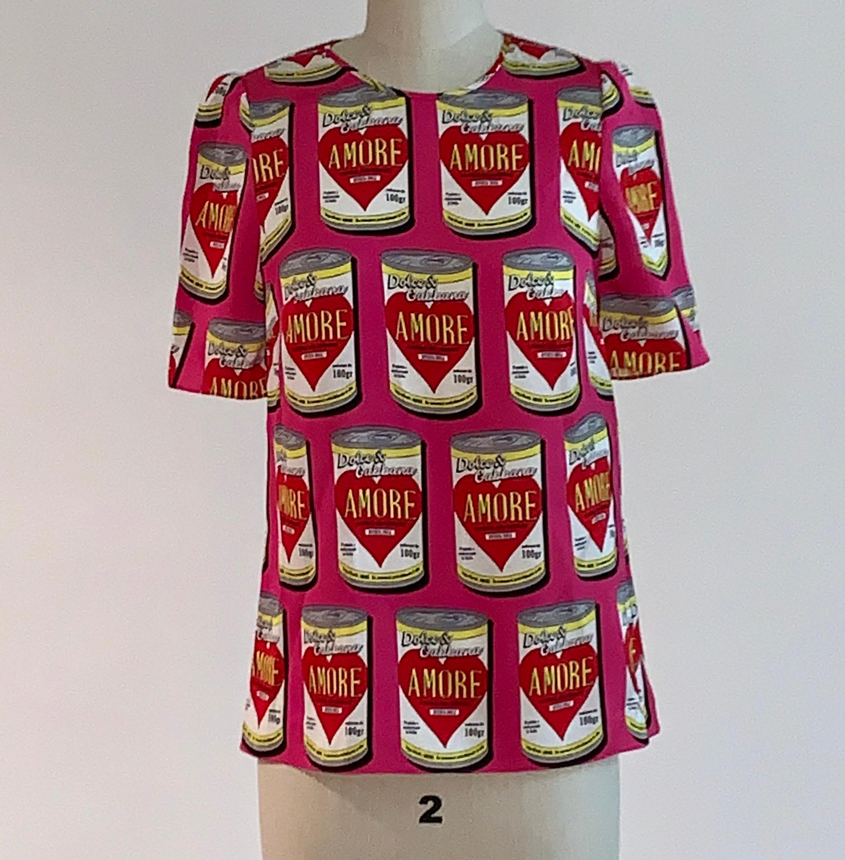 Dolce & Gabbana pink amore soup can print short sleeve blouse shirt. Back zip and hook and loop closure. 

91% silk, 9% spandex.

Made in Italy.

Size IT 38, US 2. Seen on size 2 dress form.
Bust (at underarm) 33