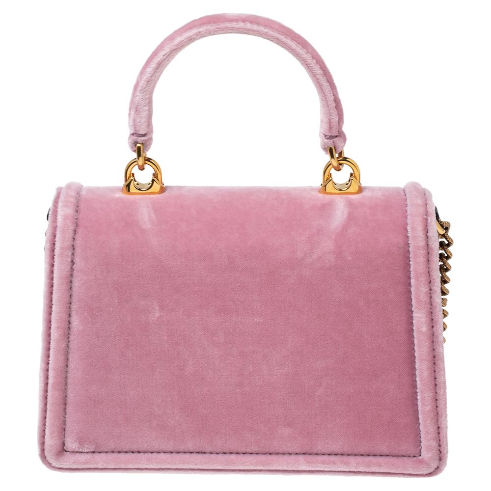Step out in style by flaunting this bag from Dolce & Gabbana. It has been crafted from pink velvet and flaunts the Devotion heart motif in gold-tone metal on the front. The bag is complete with a top handle and a shoulder chain.

Includes: Original