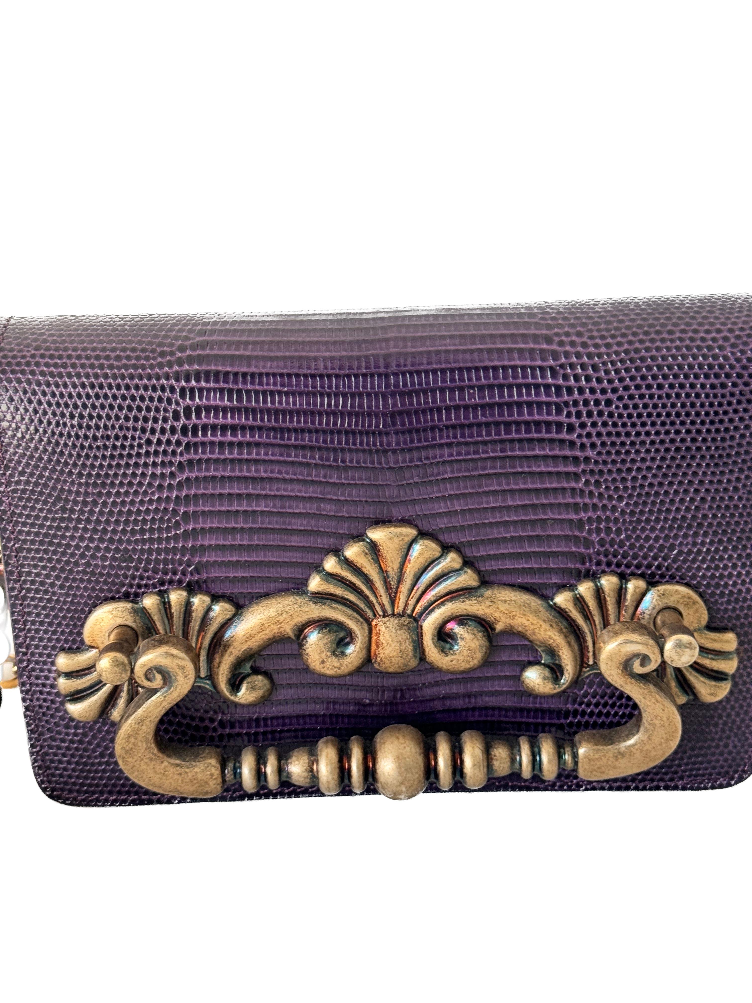 The Dolce & Gabbana Purple Lizard Evening Bag with a gold chain is an exquisite accessory that exudes luxury and sophistication. Here's an overview of this elegant piece:

Material and Color:
Crafted from luxurious lizard leather, the use of this