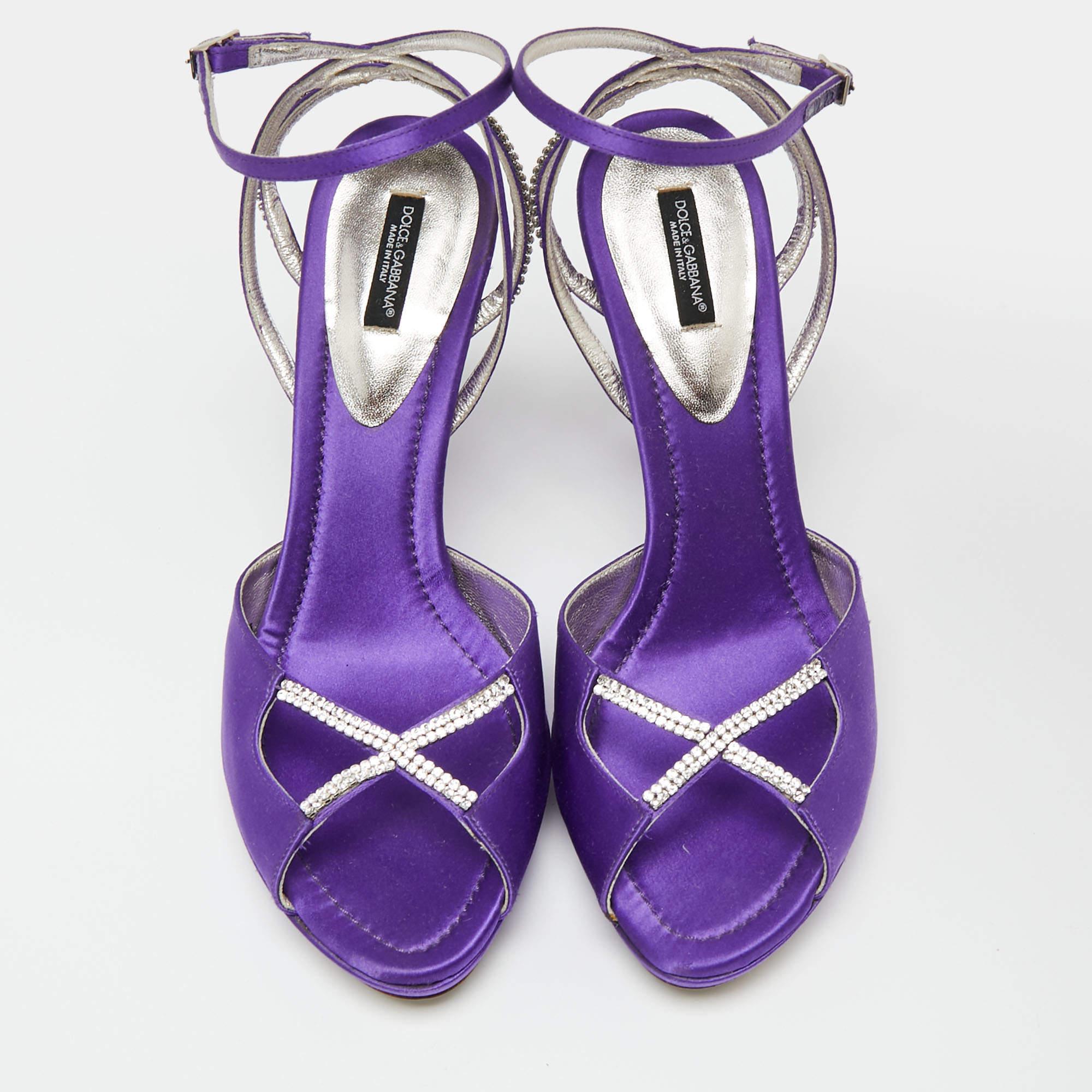 These sandals from the House of Dolce & Gabbana will add a chic touch to your outfit. They are created using purple satin, which is elevated with crystal embellishments. They flaunt open toes, an ankle strap, and slim heels. Stay stylish all day
