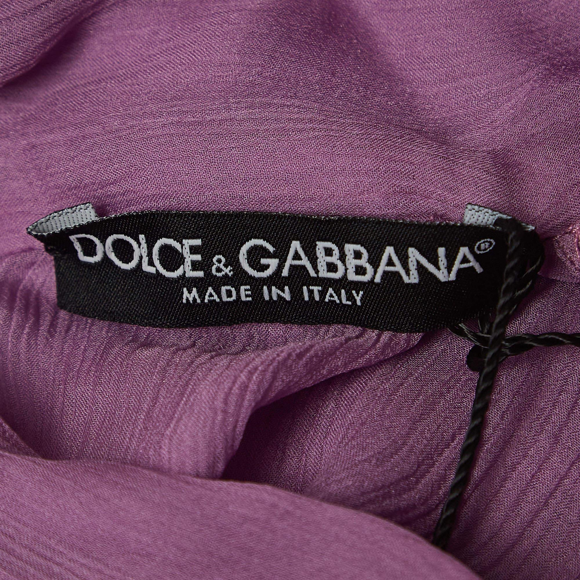 The Dolce & Gabbana blouse is a luxurious masterpiece, crafted from sumptuous silk. This elegant piece features a tasteful tie-up detail, adding a touch of sophistication. The rich purple hue enhances its allure, making it a timeless and versatile