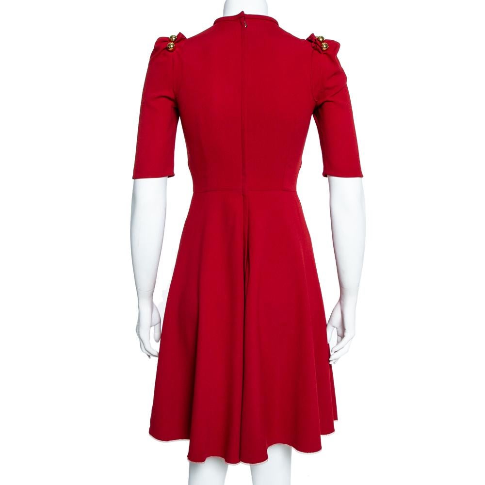 Stylish and striking, this Dolce & Gabbana dress is a must-have. It has been cut from a flowy crepe and carries a lovely shade of red. It has puff sleeves with button detailing, a simple round neckline, a fitted bodice, and an A-line skirt. It is