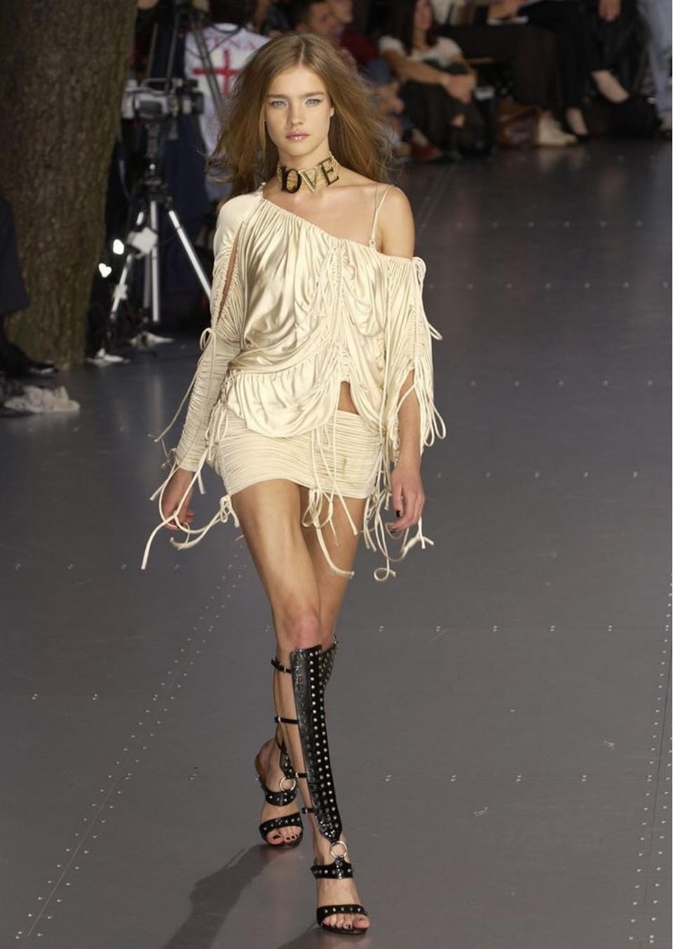 Questo è un top della collezione Primavera/Estate 2003 di Dolce & Gabbana in tonalità champagne. Il pezzo ha un design molto scultoreo, increspato e drappeggiato che riflette l'estetica sensuale e decostruita del marchio di quell'epoca.

*CHOKER NON