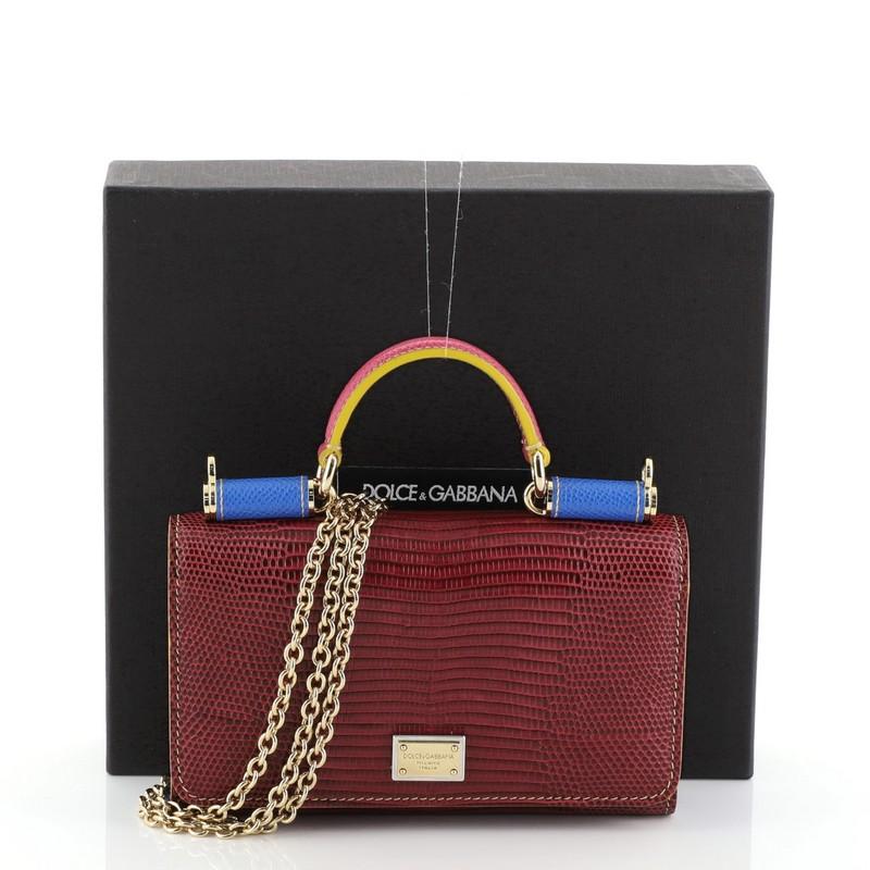 This Dolce & Gabbana Sicily Wallet on Chain Lizard Embossed Leather, crafted from blue and red lizard embossed leather, features a short top handle, designer plaque, framed top, and gold-tone hardware. Its magnetic snap closure opens to a blue