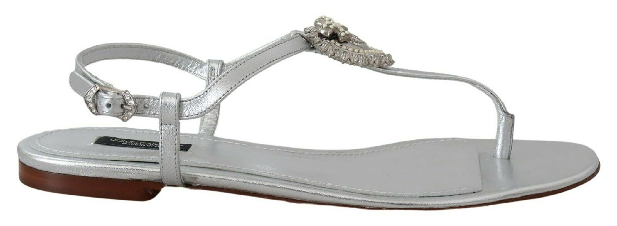 Gorgeous brand new with tags, 100% Authentic Dolce & Gabbana Devotion flat thong sandals in silver-laminated nappa leather, adorned with handmade DG Sacred Heart with metal and pearl applications. Ankle strap with jewel buckle, leather lining,