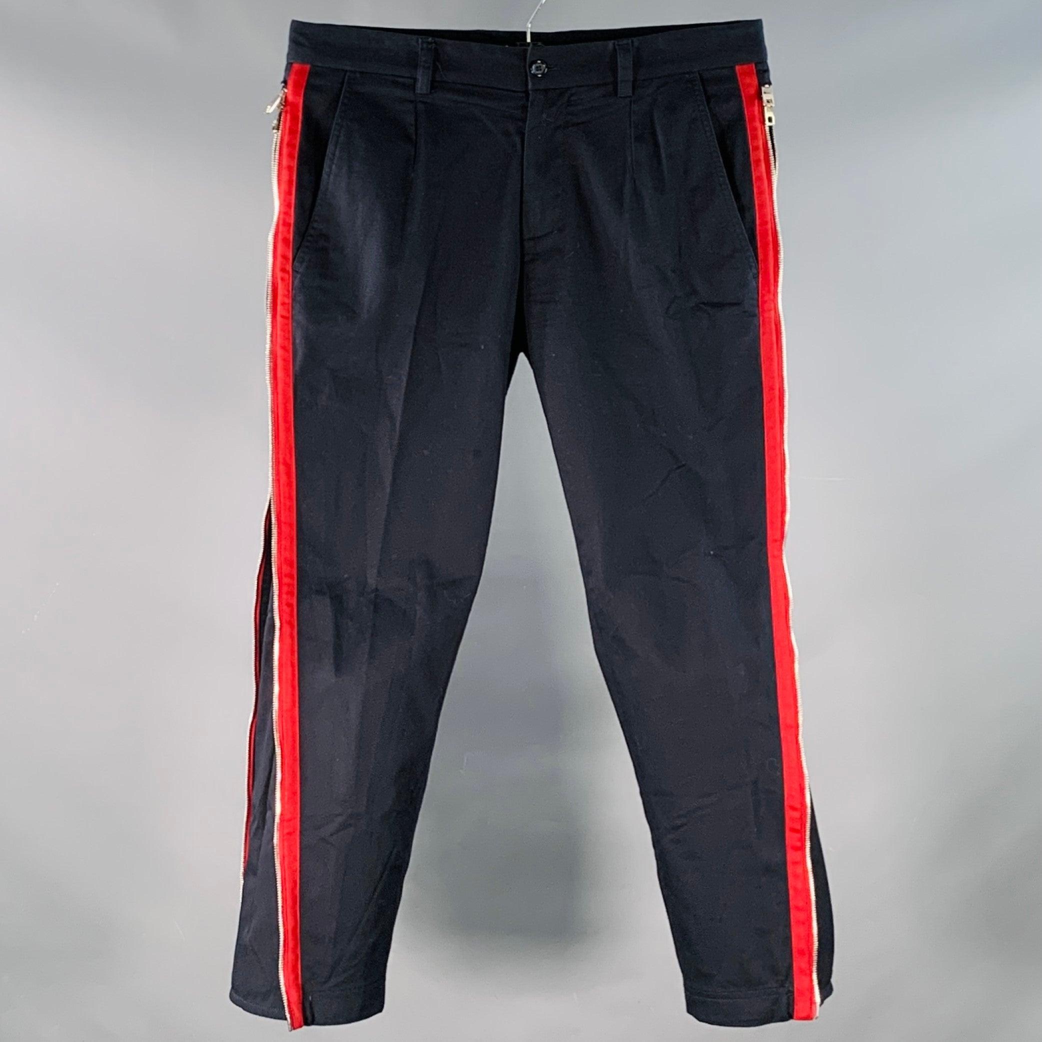 Pantalon décontracté DOLCE & GABBANA en sergé de coton mélangé extensible marine, avec bandes latérales rouges et fermeture éclair en métal argenté, jambe fuselée et fermeture à glissière. Les fermetures éclair à rayures latérales offrent des