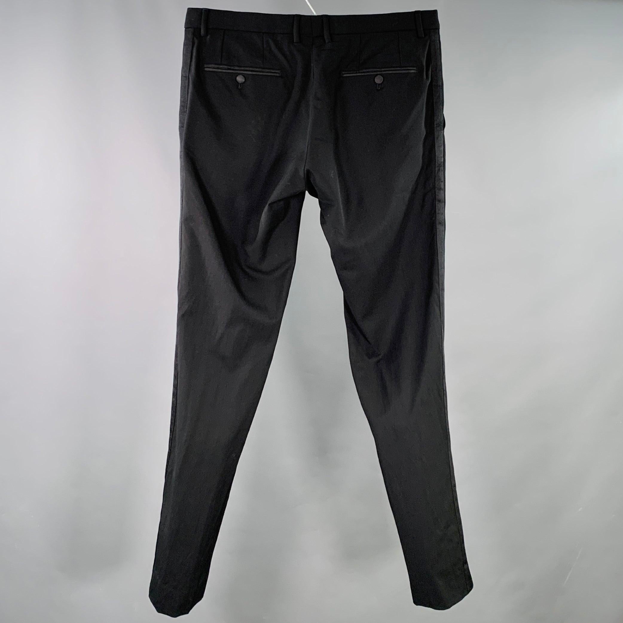 DOLCE & GABBANA dress pants
in a black wool silk twill featuring tuxedo side stripes, tapered fit, and zip fly closure. Hem has been left unfinished in order to tailor to your perfect fit. Made in Italy.Excellent Pre-Owned Condition. 

Marked:   IT
