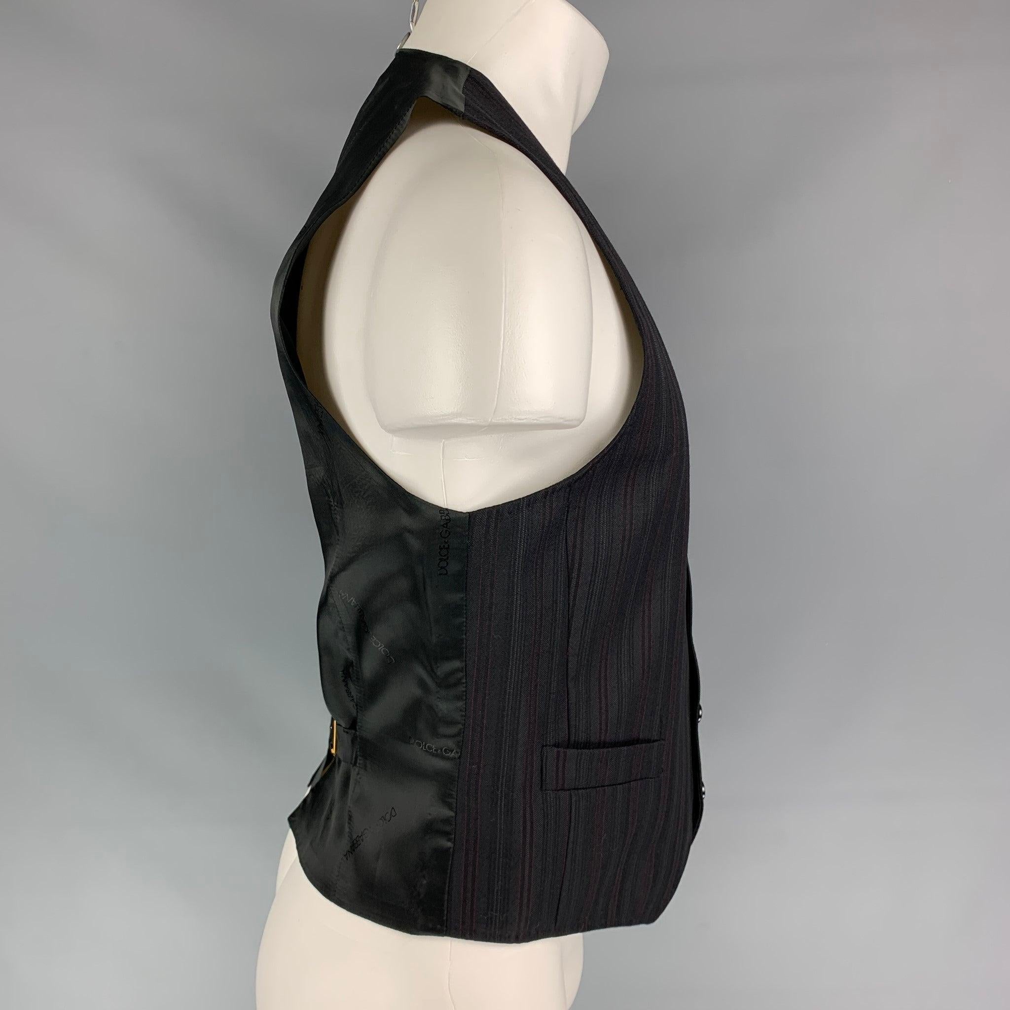 DOLCE & GABBANA vest comes in a black & burgundy stripe wool featuring a classic style, back belt, slit pockets, and a buttoned closure. Made in Italy.
Very Good
Pre-Owned Condition. 

Marked:   48 

Measurements: 
 
Shoulder: 13.5 inches  Chest: 38