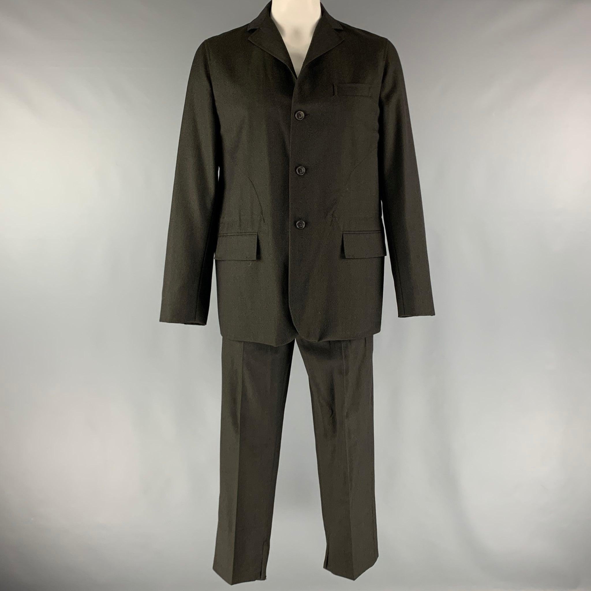 DOLCE & GABBANA suit comes in a black wool twill material with a no liner and includes a single breasted, four button sport coat with a notch lapel, flap pockets, zipper cuffs, and matching flat front trousers. Made in Italy.Good Pre-Owned