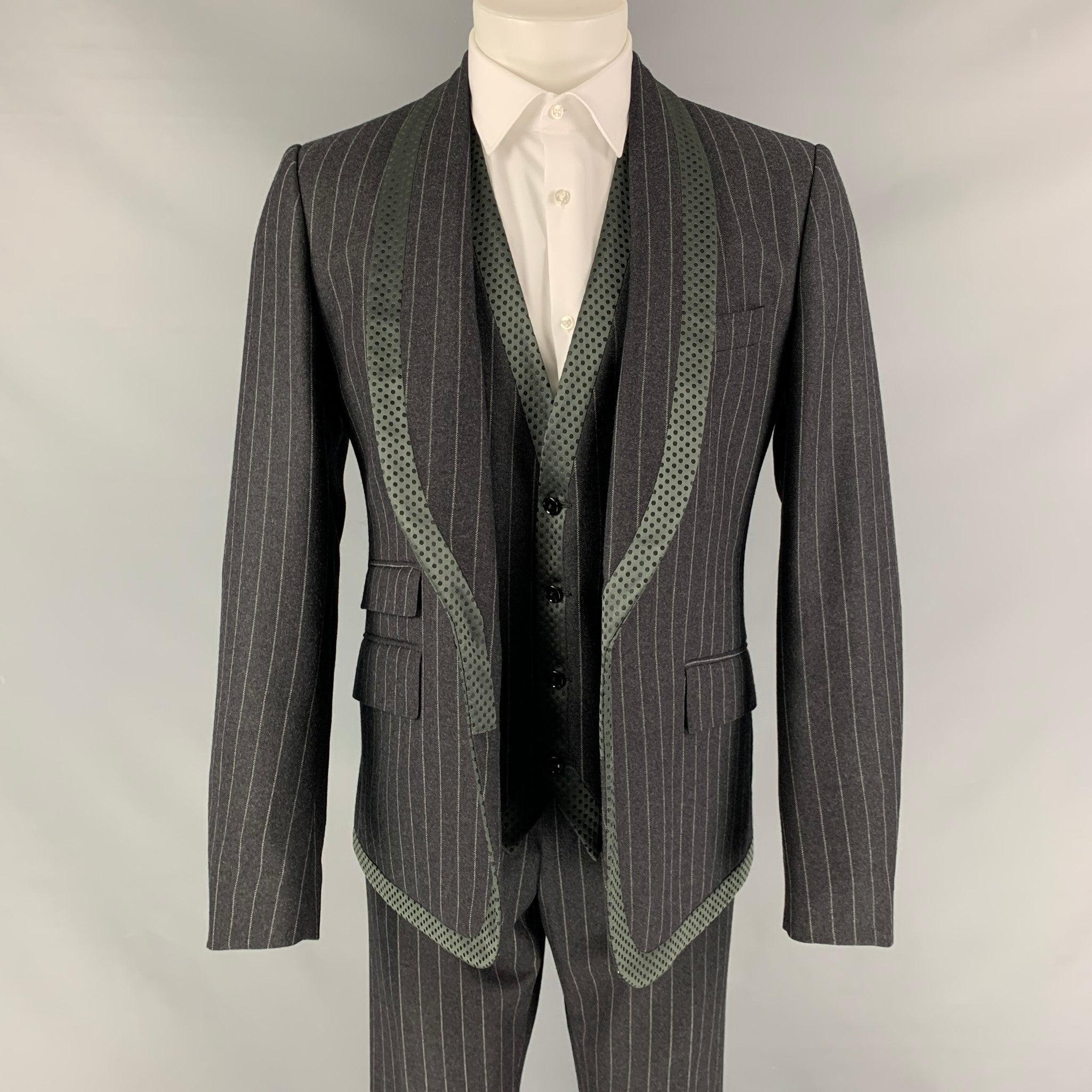 DOLCE & GABBANA 3 Piece
suit comes in a gray chalkstripe virgin wool with a full liner and includes a single breasted, single button sport coat with shawl collar and a matching vest and flat front trousers. Waist and length of pants need to be