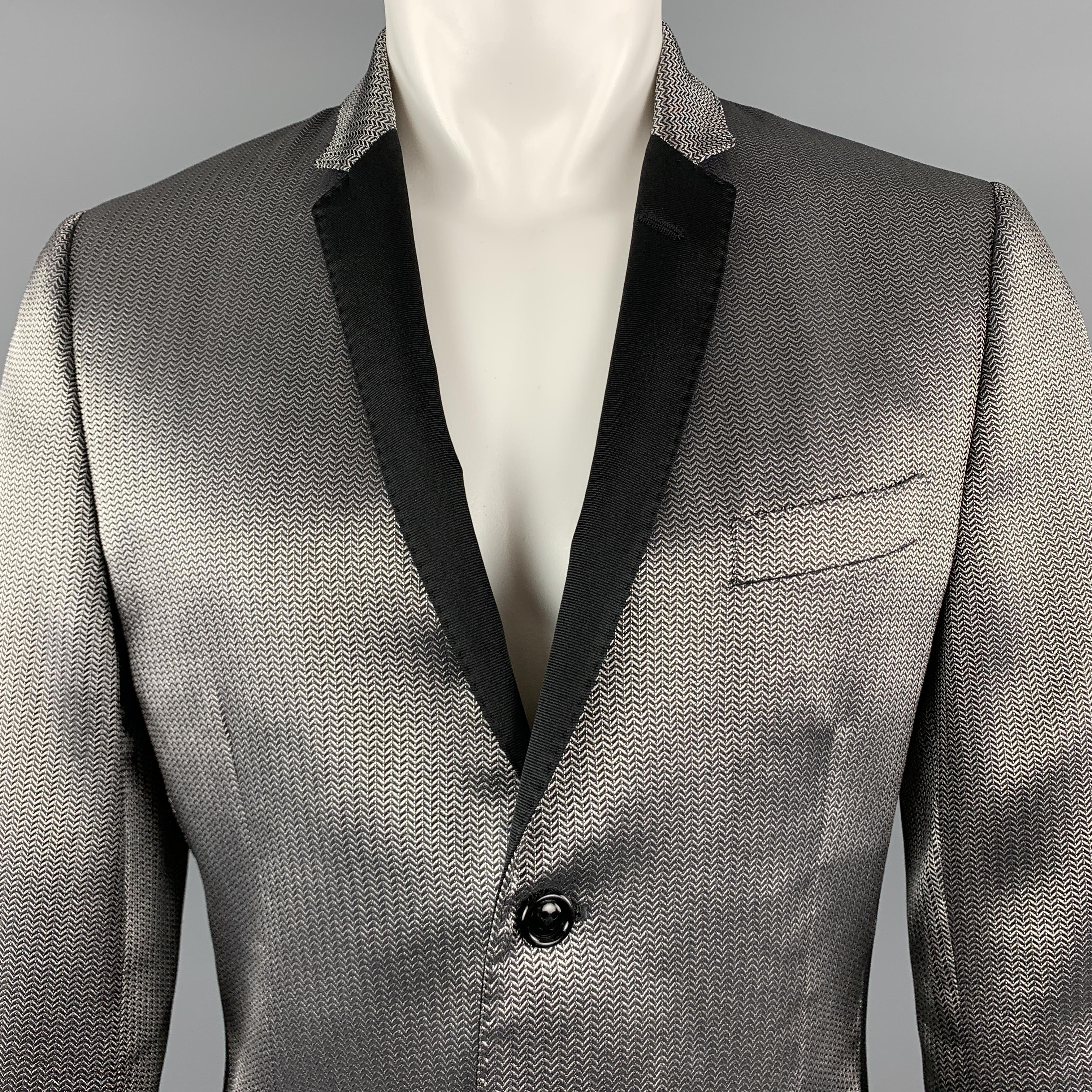 DOLCE & GABBANA sport coat comes in silver metallic herringbone with a slim black notch lapel, single breasted, three button front, and ventless back. Minor wear on back. As-is. Made in Italy.

Very Good Pre-Owned Condition.
Marked: IT