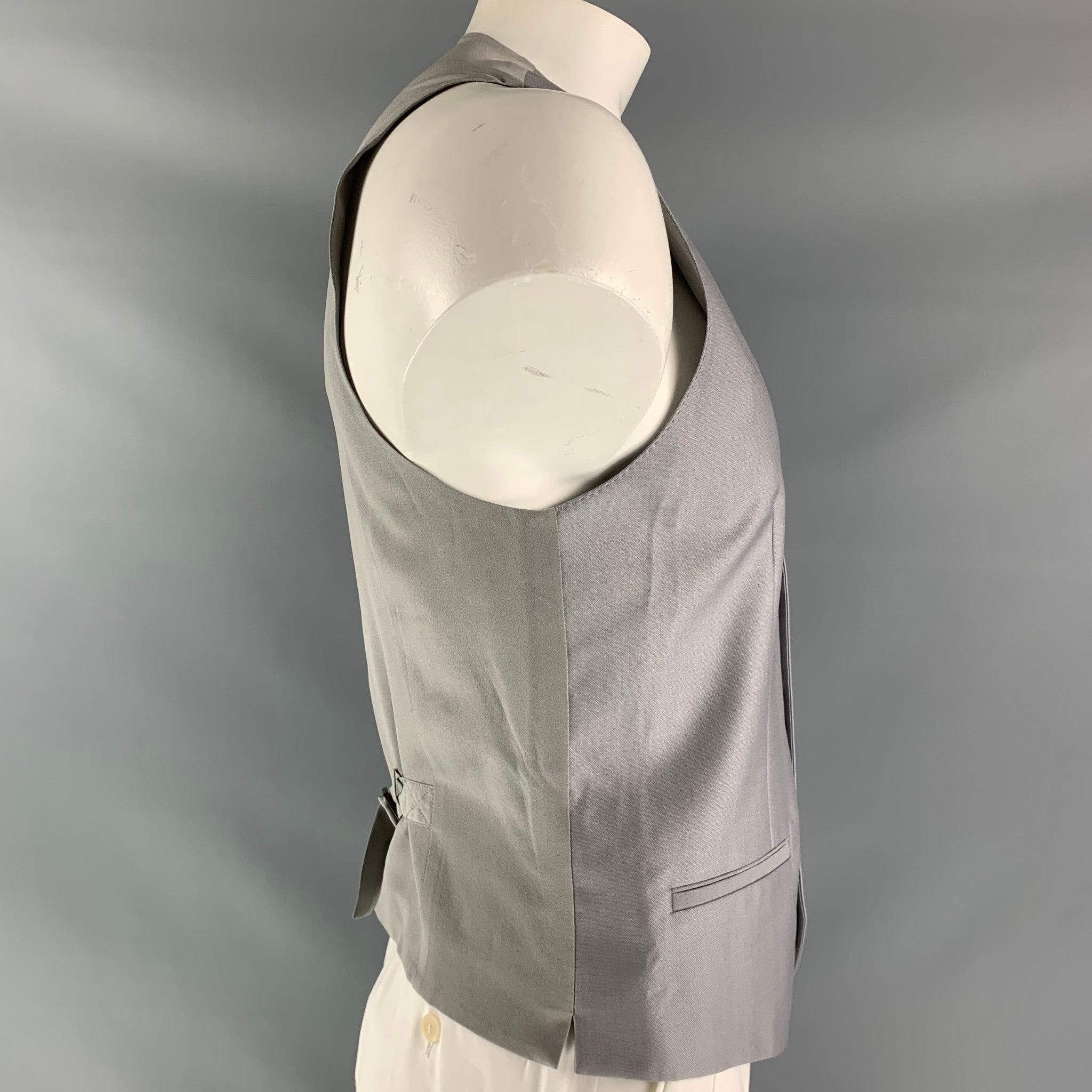 DOLCE & GABBANA dress vest comes in light gray wool fabric, full lined featuring V-neck, welt pockets, five buttons down closure, grey silk fabric at back and adjustable belt. Made in Italy.Excellent Pre-Owned Condition.  

Marked:   58 IT