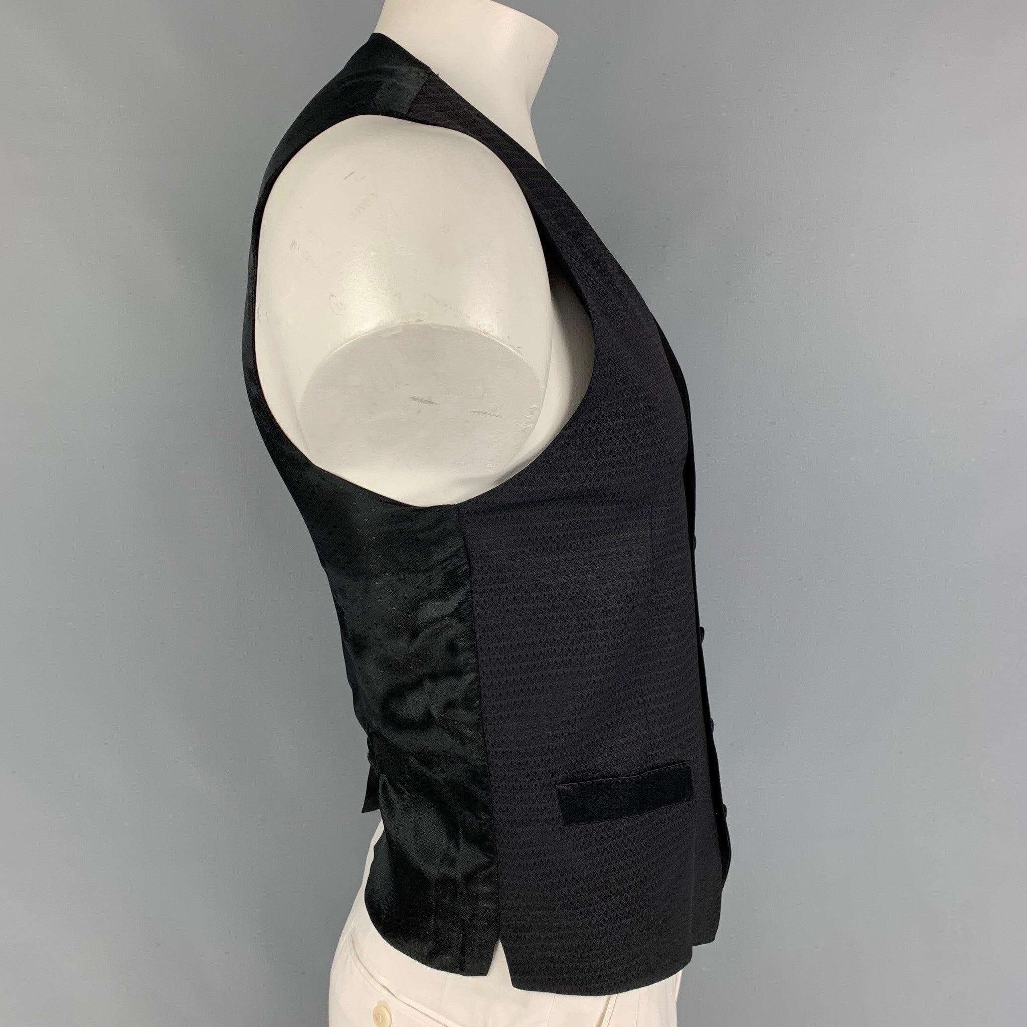 DOLCE & GABBANA vest comes in a black jacquard wool blend featuring a back belt, slit pockets, and a buttoned closure. Made in Italy.
Very Good
Pre-Owned Condition. 

Marked:   52 

Measurements: 
 
Shoulder: 15 inches  Chest:
38 inches  Length: