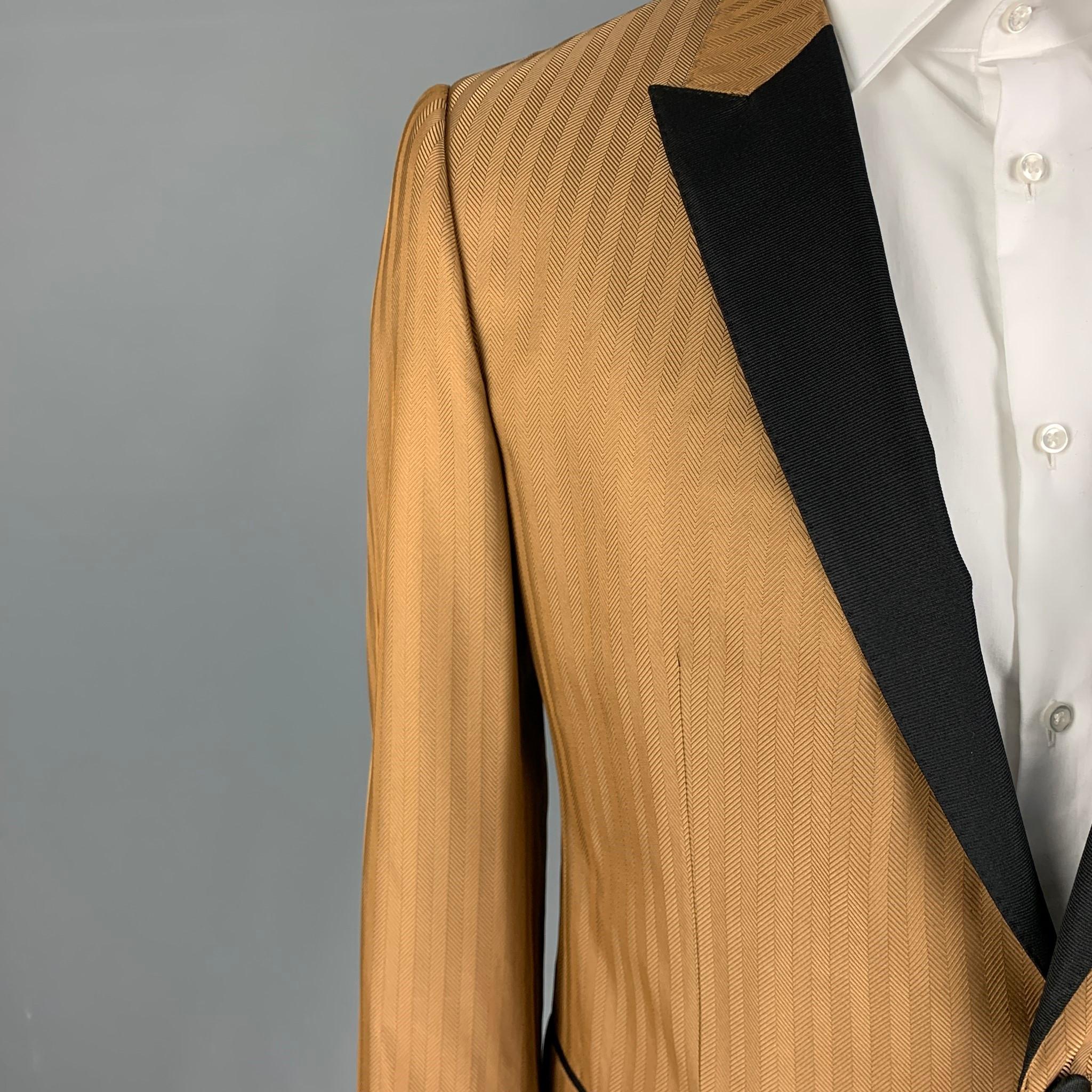 DOLCE & GABBANA sport coat comes in a tan herringbone silk blend with a full liner featuring a black peak lapel, flap pockets, single back vent, and a double button closure. Made in Italy. 

Excellent Pre-Owned Condition.
Marked: