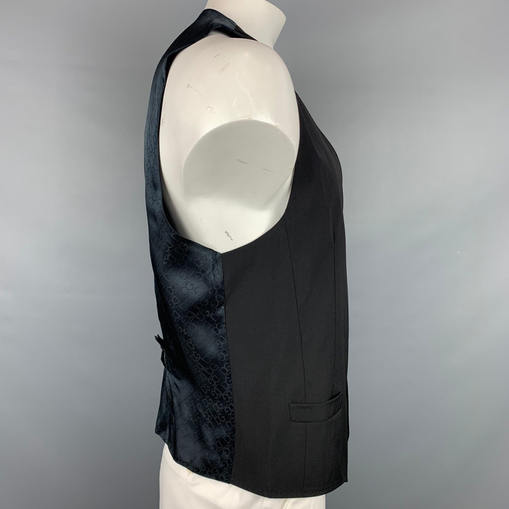 DOLCE & GABBANA vest comes in a black wool with a monogram back print featuring a back belt, slit pockets, and a buttoned closure. Made in Italy.Very Good
Pre-Owned Condition. 

Marked:   Size tag removed.  

Measurements: 
 
Shoulder: 15 inches 