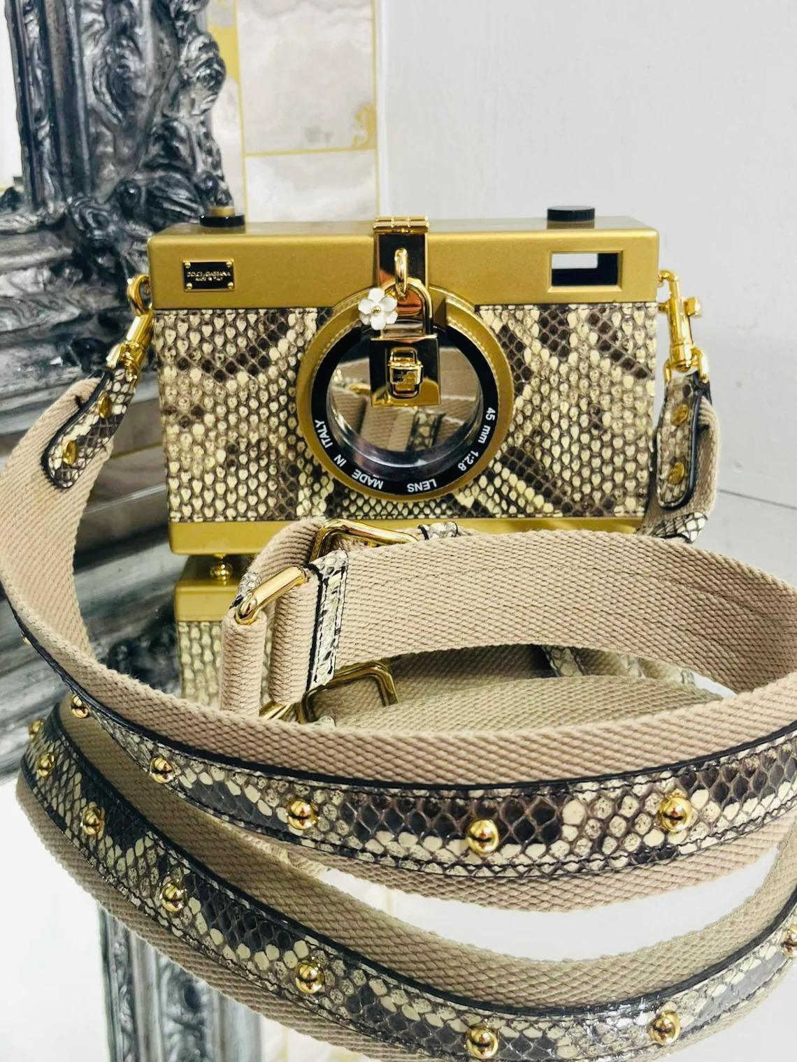 Dolce & Gabbana Snakeskin Camera Bag

Brown snakeskin, cross body bag, hardcase camera bag. Gold hardware, decorative padlock with white enamel flower. Turn lock closure, lens. Removable, canvas, studded snakeskin, shoulder strap. From 2016 runway