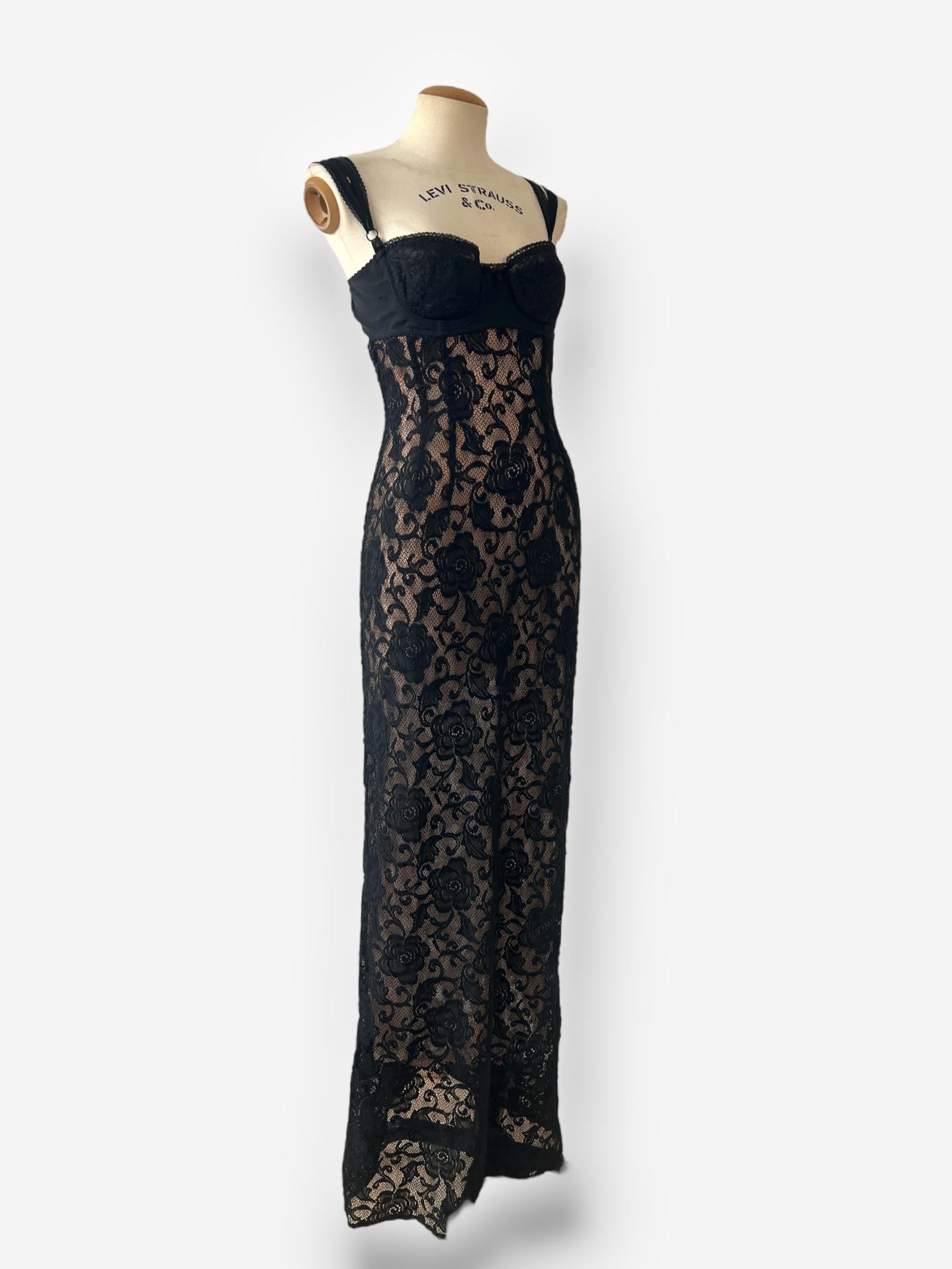 Dieses atemberaubende Vintage-Meisterwerk aus der kultigen Frühjahr/Sommer-Kollektion 1997 von Dolce & Gabbana ist ein schwarzes Spitzen-Maxikleid, das Eleganz und subtile Sinnlichkeit perfekt ausbalanciert. Das Kleid verfügt über einen angenähten
