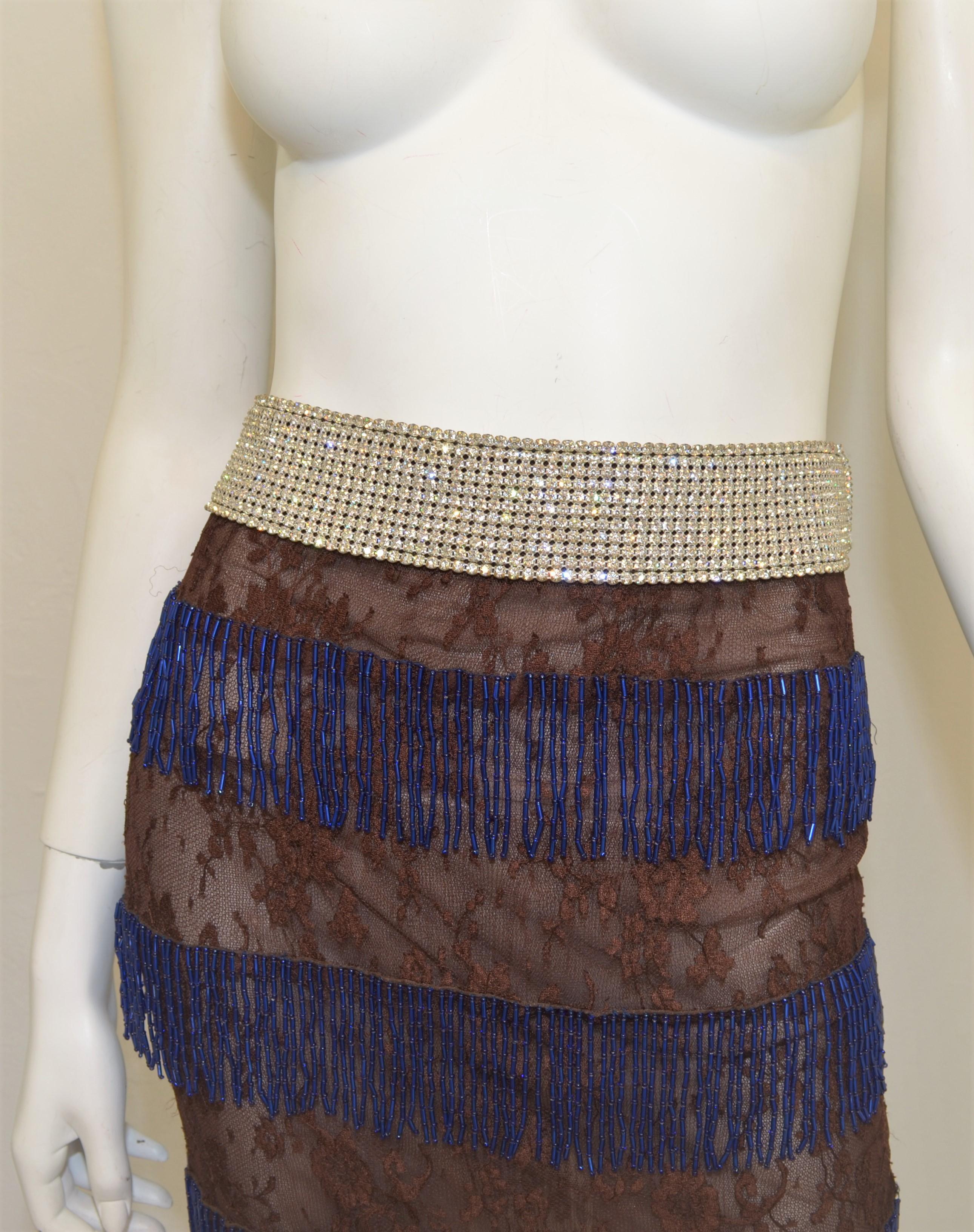 Dolce & Gabbana Brown lace skirt with a rhinestone encrusted waistband and blue fringed bead-work. Skirt has a back zipper closure. Labeled Size 42, viscose and nylon blend, full lining. Made in Italy.

Measurements:
Waist 31”, hips 34”, length 33”
