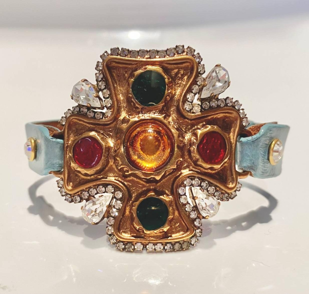 Dolce & Gabbana bracelet featuring frontal flower shaped brass structure embellished with multicolor stones and crystals, aqua color leather strap with gold tone metalware closure and logo initial details

Condition: 2000s, very good, slight wear,