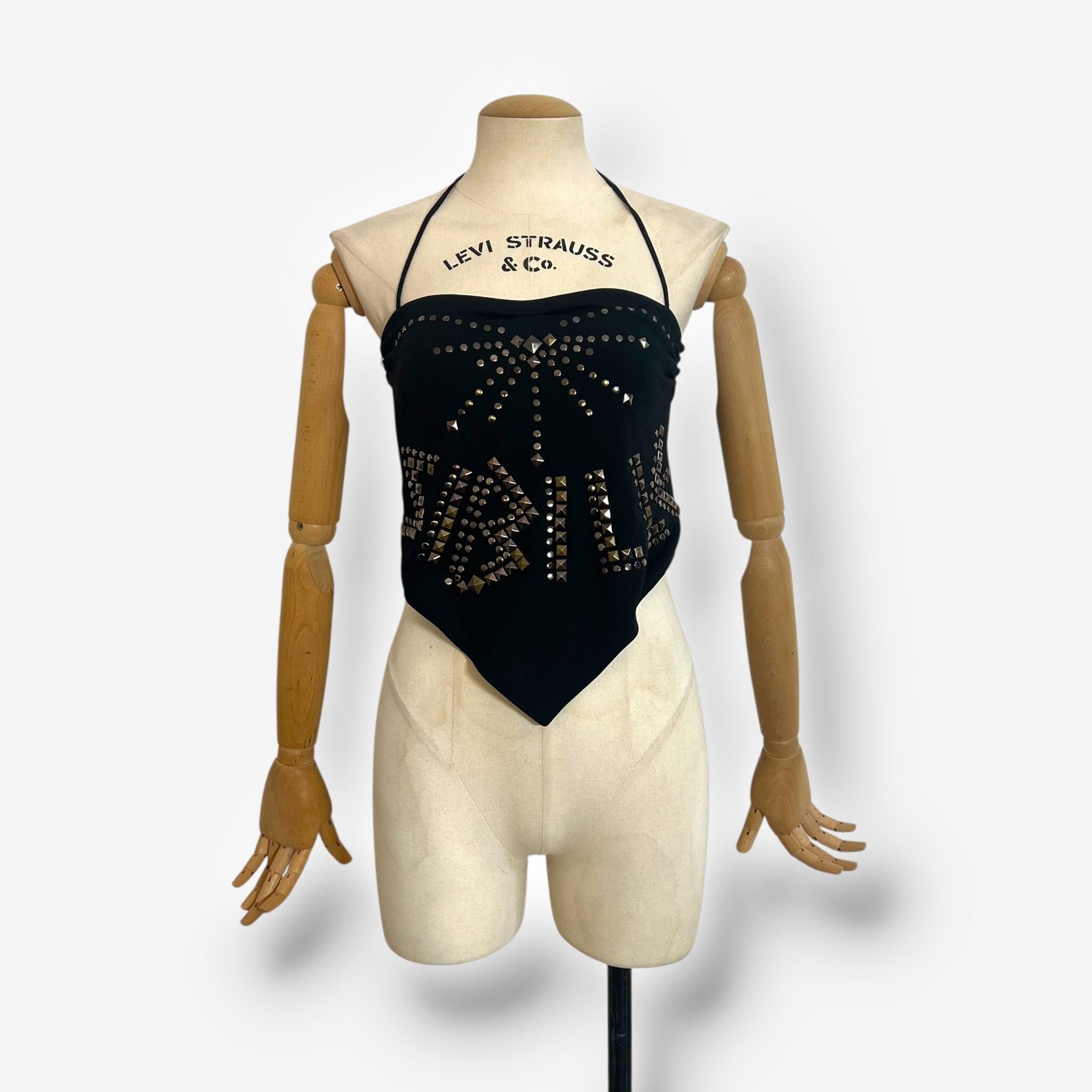 A standout from the S/S 2003 collection, this Dolce & Gabbana halter top is crafted in a scarf-style silhouette with dramatic flair. Made in a soft black stretch fabric, it features bold gold-tone studs spelling out “Thrill” across the front,