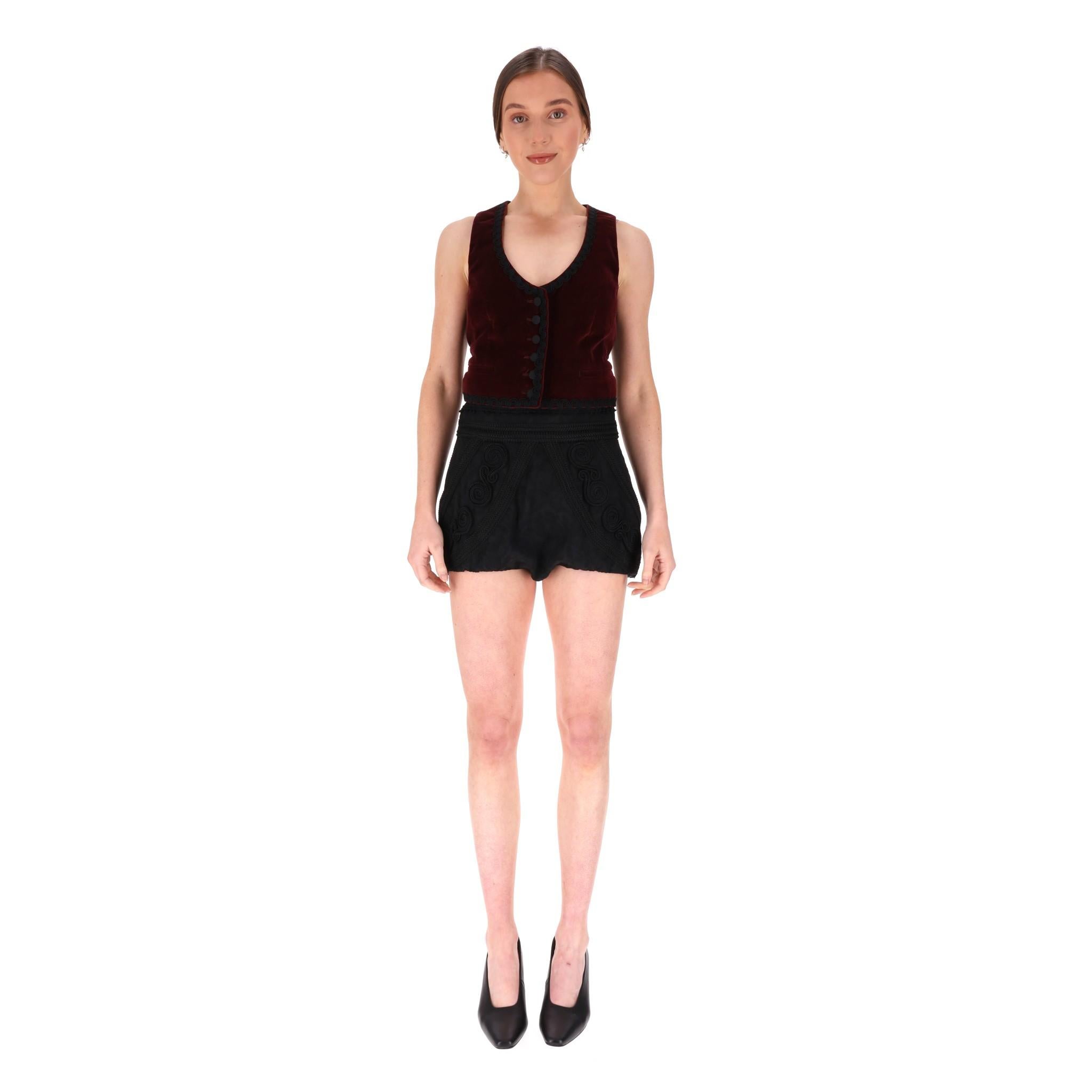 Dolce &Gabbana Velvet Waistcoat & Embroidered Shorts Set

The vest features a rich burgundy velvet front adorned with wavy trim details throughout.

It has a button-up front closure and a contrasting black back.

The shorts are made from a silk and