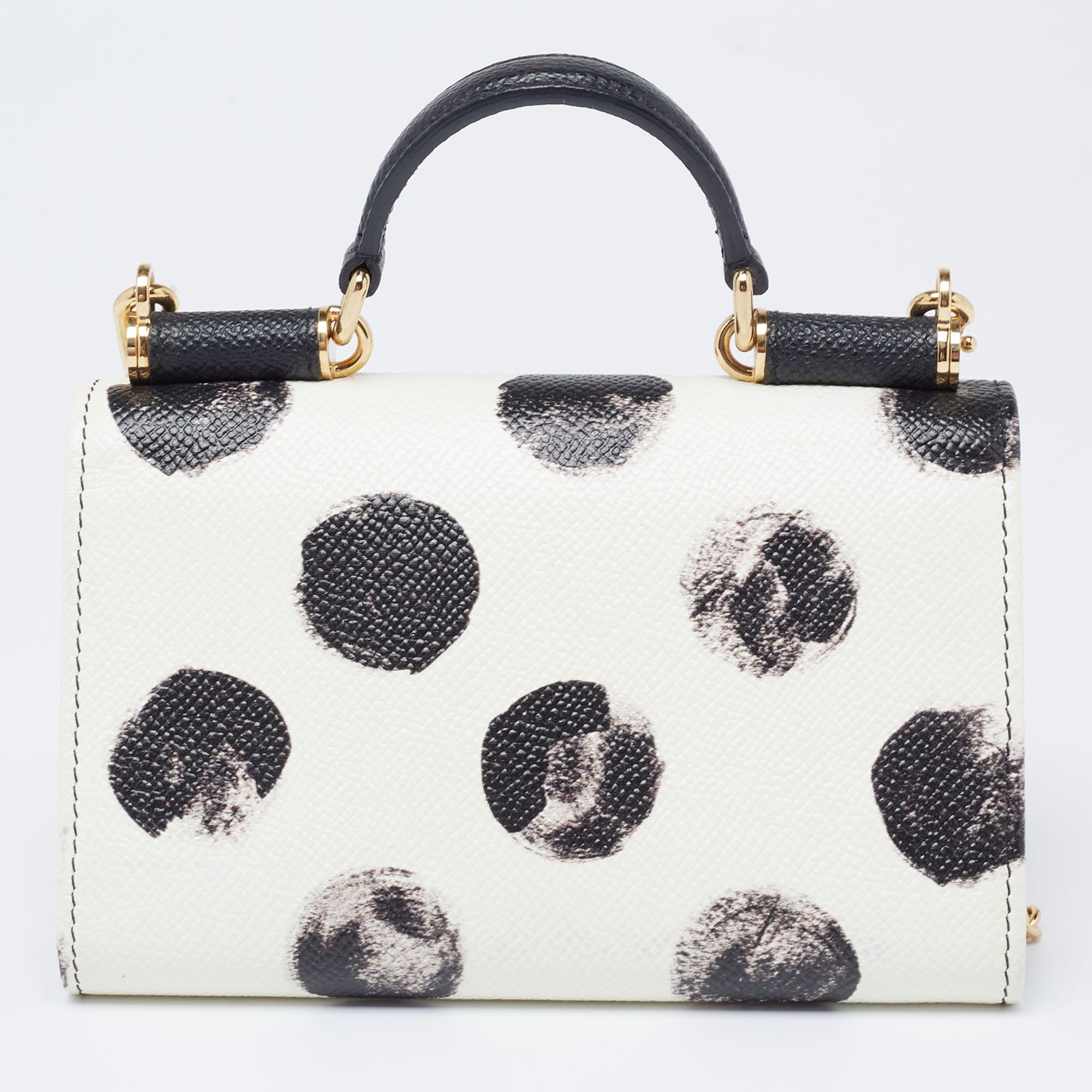 Displaying a graceful silhouette and a sturdy design, this fascinating Miss Sicily Von wallet on chain from Dolce & Gabbana rightly represents the brand's skilled flair. It is made from black-white polka-dot leather, with a gold-toned logo plaque