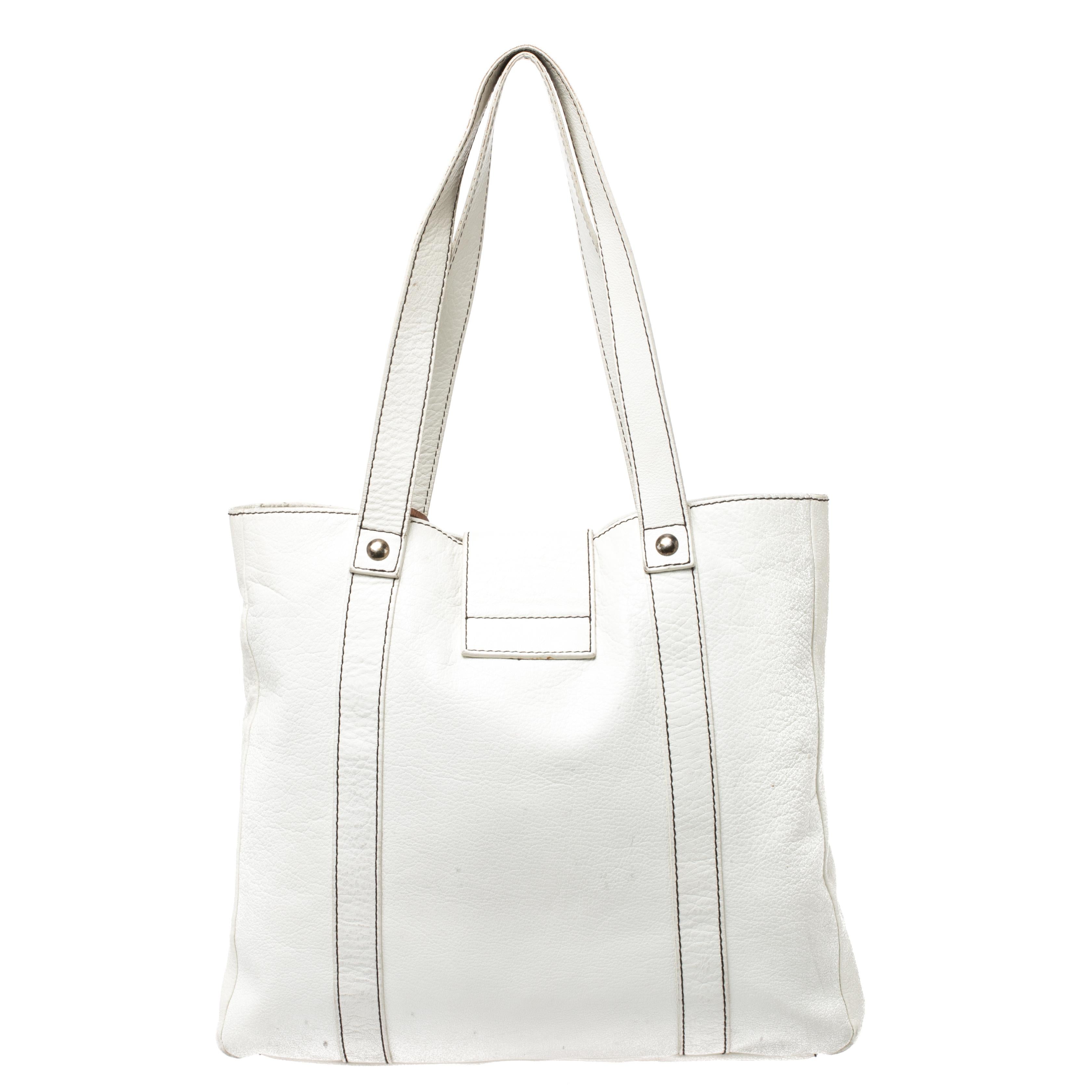 This Dolce & Gabbana tote is the perfect bag to add to your collection. Featuring a white leather body, this bag is secured with an exaggerated buckle at the front. It comes with dual top handles, dangling charms and offers ample room to stow all