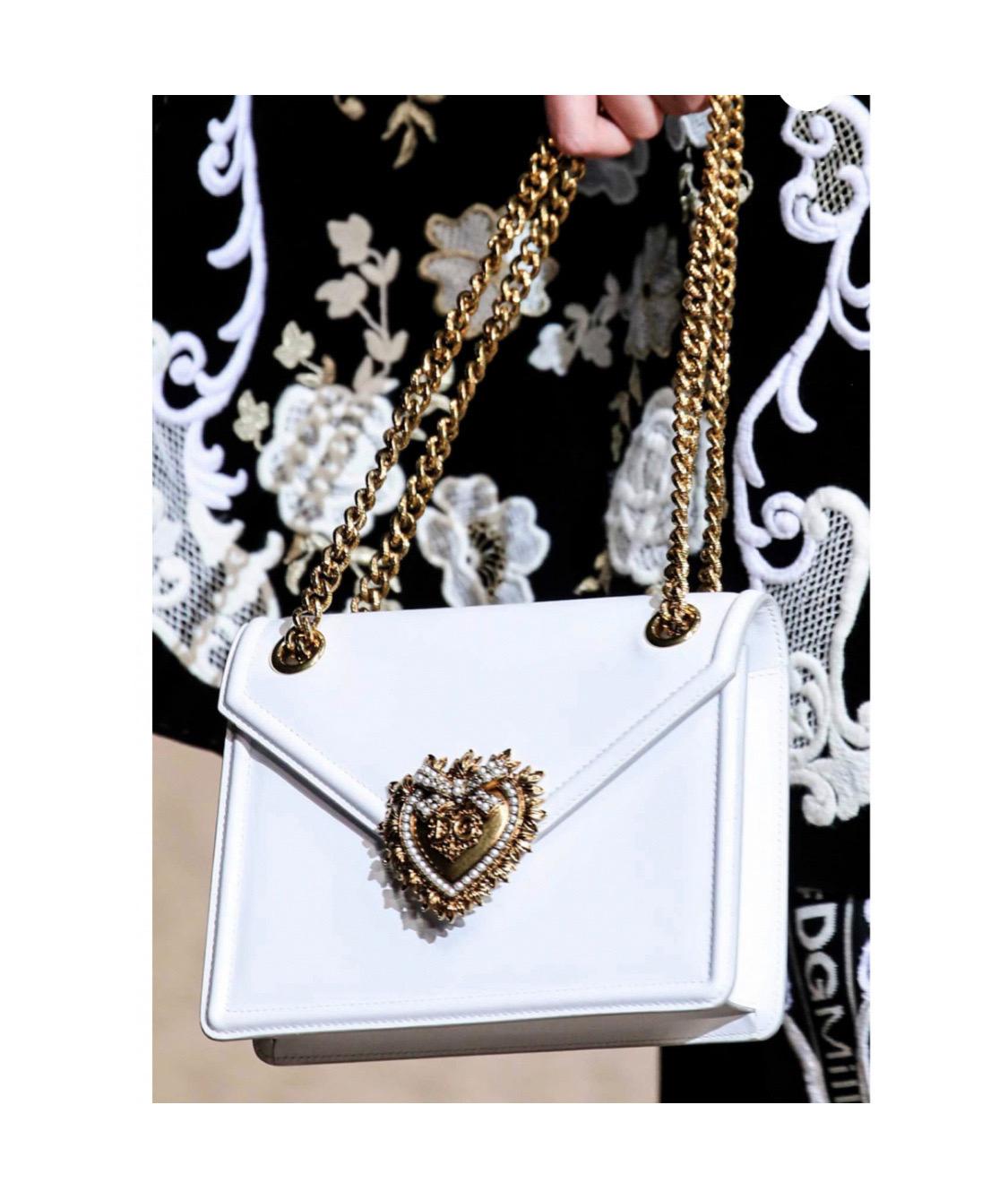 Turn heads with this smooth calf white
leather Devotion crossbody bag by
Dolce & Gabbana. Featuring a stunning
sliding ridged chain shoulder strap and
logo heart seal with gold and pear!
details.

Made in Italy.

Size: 20 x 15 x 4cm

100%