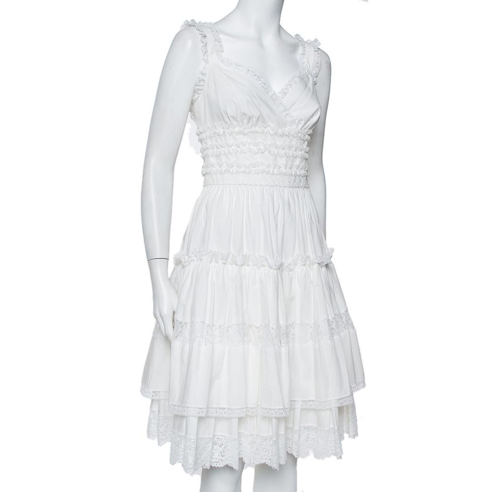 This dreamy Dolce & Gabbana mini dress will immediately transport you to the world of high-fashion. The white creation has been designed with lace trims and exhibits a flattering silhouette with tiered details. It is equipped with a zip closure at