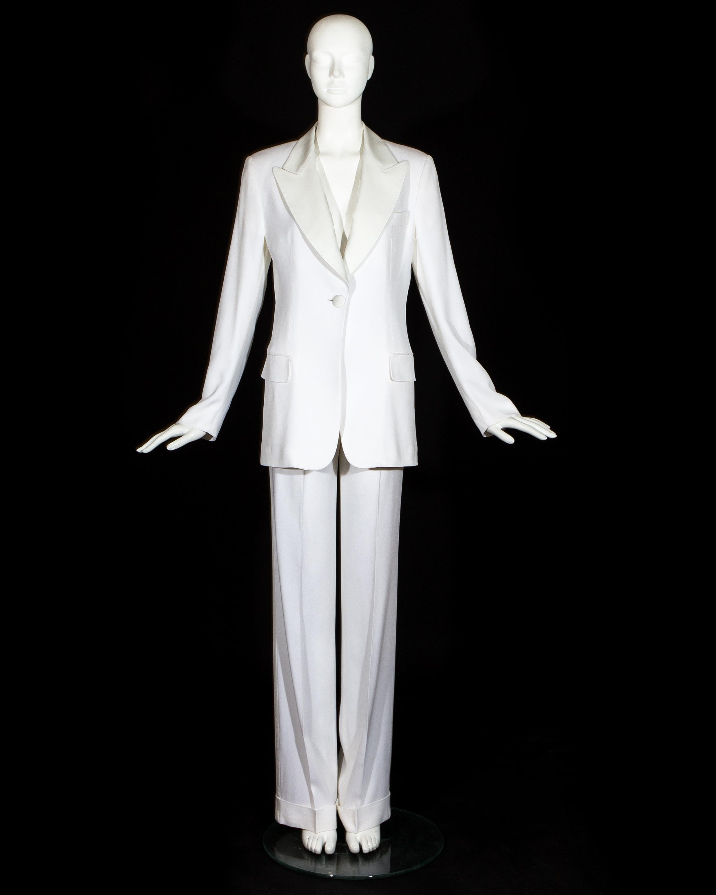 Combinaison pantalon inspirée de Bianca Jagger. Crêpe blanc avec revers et boutons en soie. Pantalon ample et veste de blazer ajustée.

Printemps-été 1995