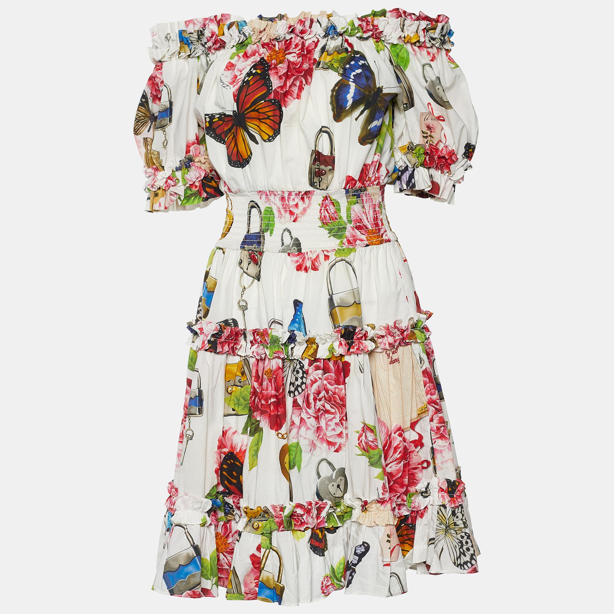 Feel summer-ready and chic with this dress from Dolce & Gabbana. Doused in multicolored padlock and garden prints, this midi dress is created from white cotton fabric. Featuring an off-shoulder silhouette, this dress is further beautified with short