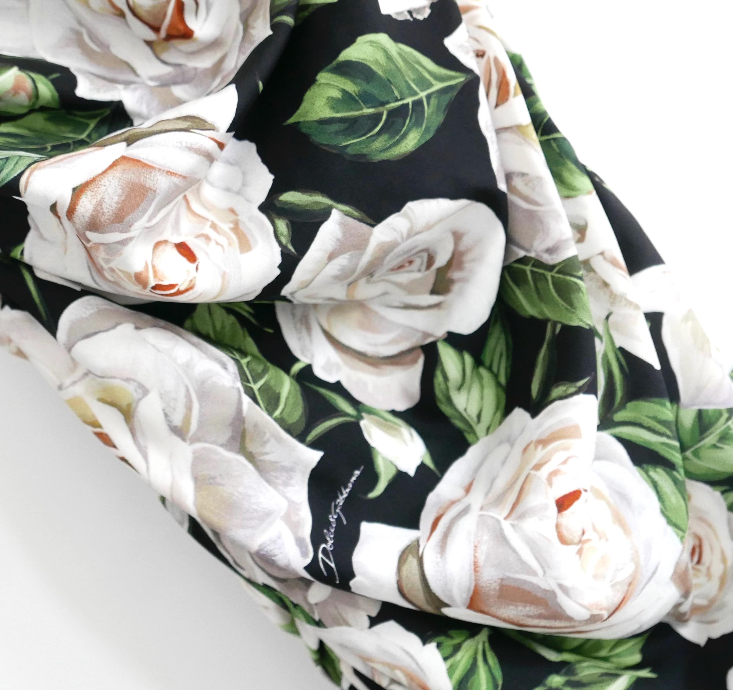 Ikonisches Kleid mit weißem Rosendruck von Dolce & Gabbana. Gekauft für £1850 und neu mit Tags. Aus superweicher weißer Seide mit Rosendruck und schwarzem Seidenfutter. Es hat einen sehr schmeichelhaften, figurbetonten Schnitt mit gerafften Seiten,
