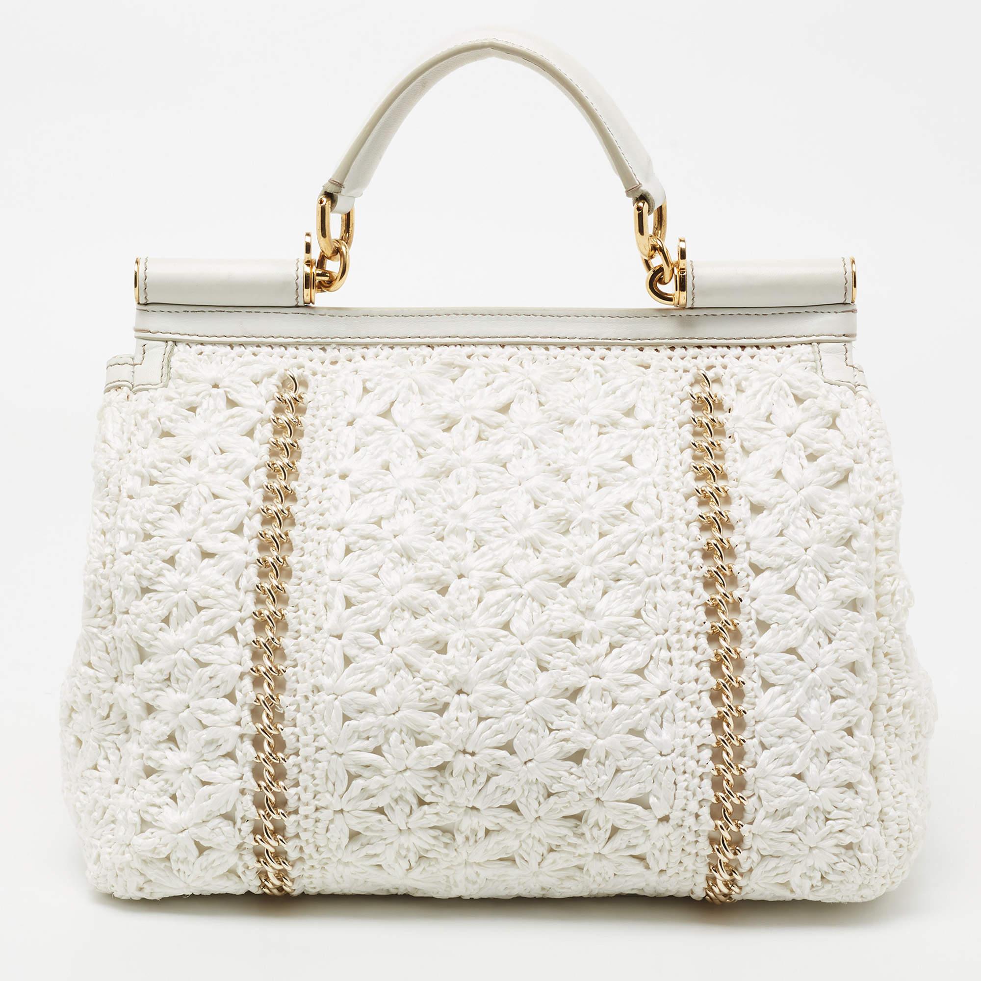 Meticulously crafted into an eye-catchy shape, this Miss Sicily tote from Dolce & Gabbana exudes just the right amount of charm and elegance! It is made from white straw crochet, with a logo plaque embellishing the front. It has a spacious interior,