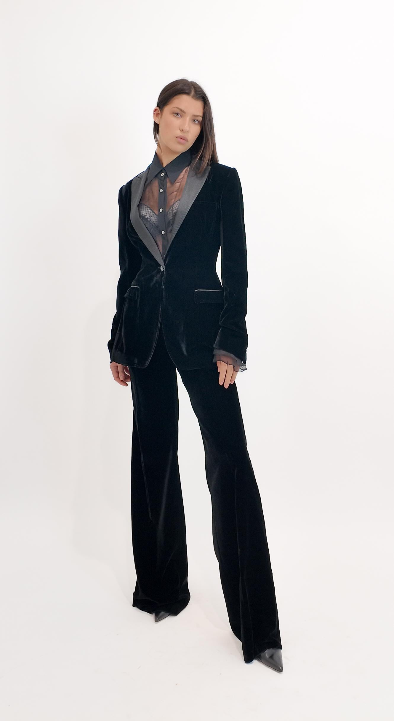 Eleva il tuo stile da sera con lo smoking a gamba larga in velluto nero di Dolce & Gabbana. Caratterizzato da una raffinata silhouette anni '70, questo pezzo di lusso combina una raffinatezza senza tempo con un'eleganza moderna. Il suo taglio a