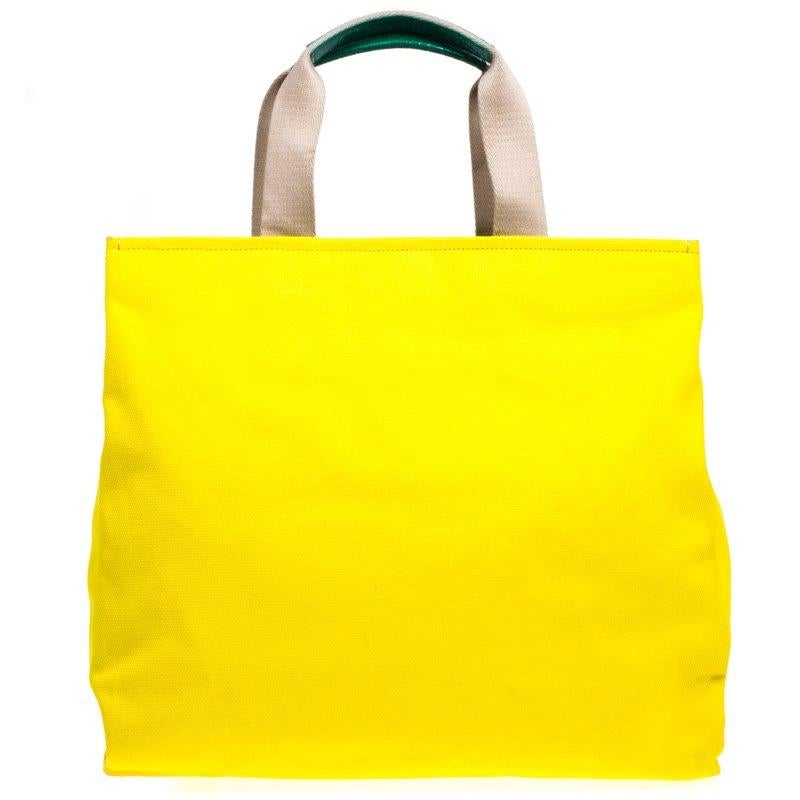 This adorable Maria shopper tote from Dolce and Gabbana is made from yellow canvas. The bright bag has a cute family patch on the front and dual top handles. The buttoned closure opens to a satin lined polka dot print interior. Shop in style with