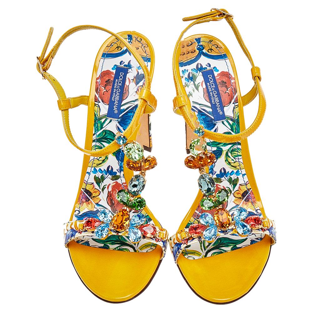 These stylish and playful sandals by Dolce & Gabbana are perfect for summer days and vacations. Crafted from patent leather, they come in a bright yellow hue with floral-printed vamps, insoles, and block heels. They are styled with open toes and